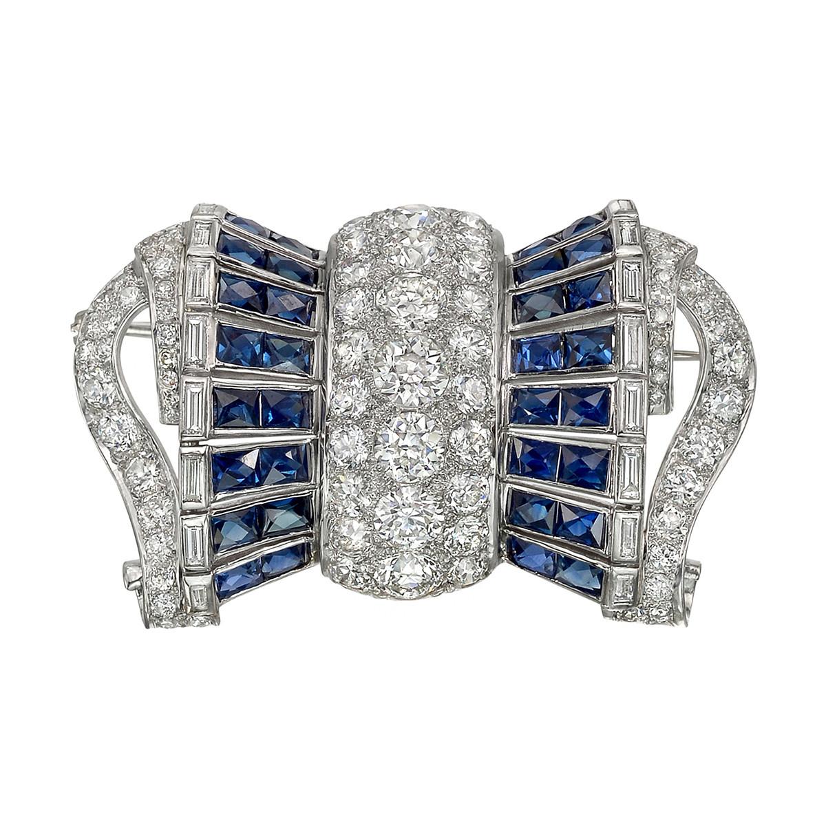 Barrel-shaped bow pin, featuring old European-cut diamonds, baguette-cut diamonds and scissor-cut dark blue sapphires, set in platinum. Diamonds weighing approximately 11.25 total carat and sapphires weighing approximately 7.00 total carats. 2