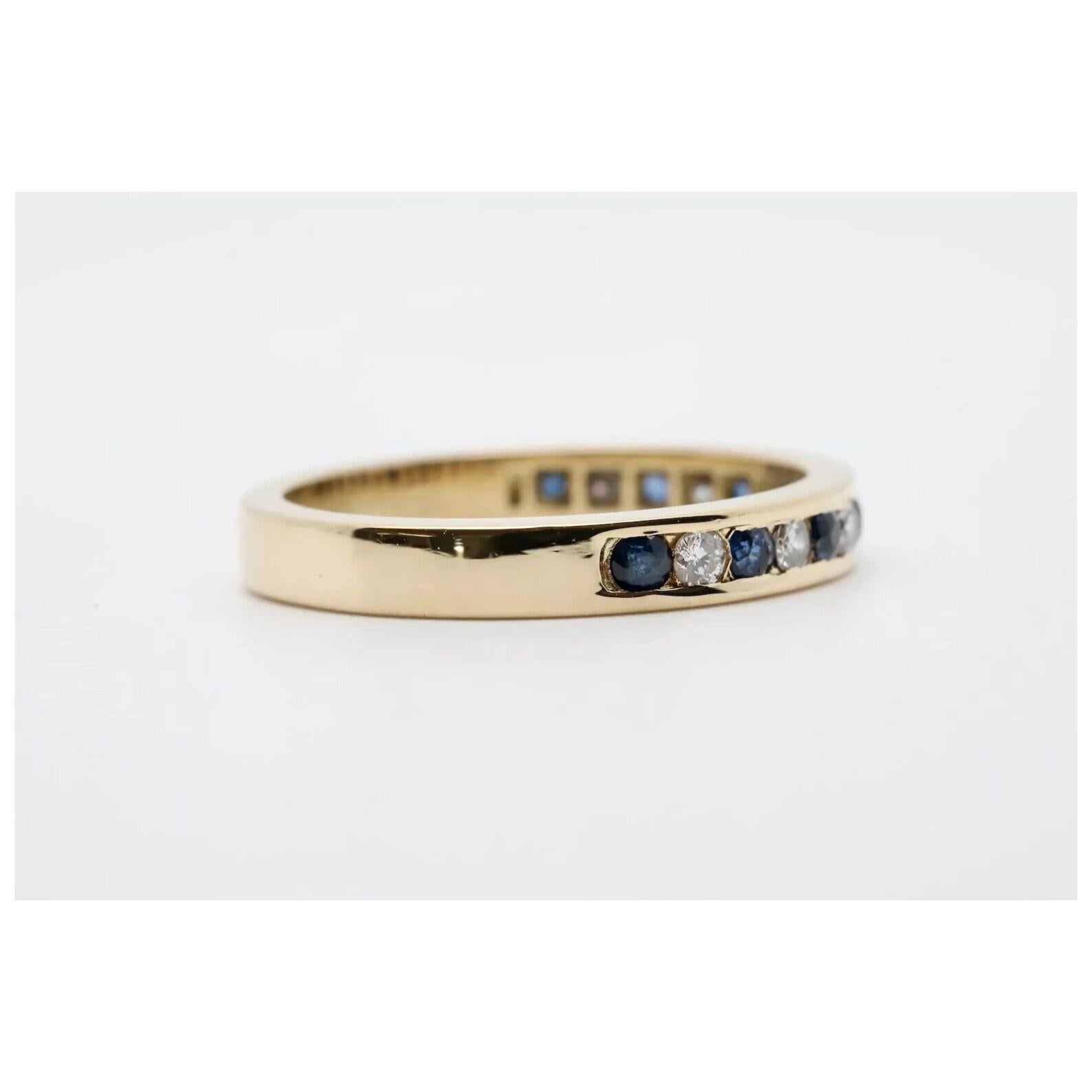 A vintage sapphire, and diamond wedding band in 18 karat gold. Channel set with 7 brilliant cut diamonds and 8 brilliant cut sapphires in richly polished yellow gold. The diamonds weigh a combined 0.14 carats and grade as H color, VS1 clarity with