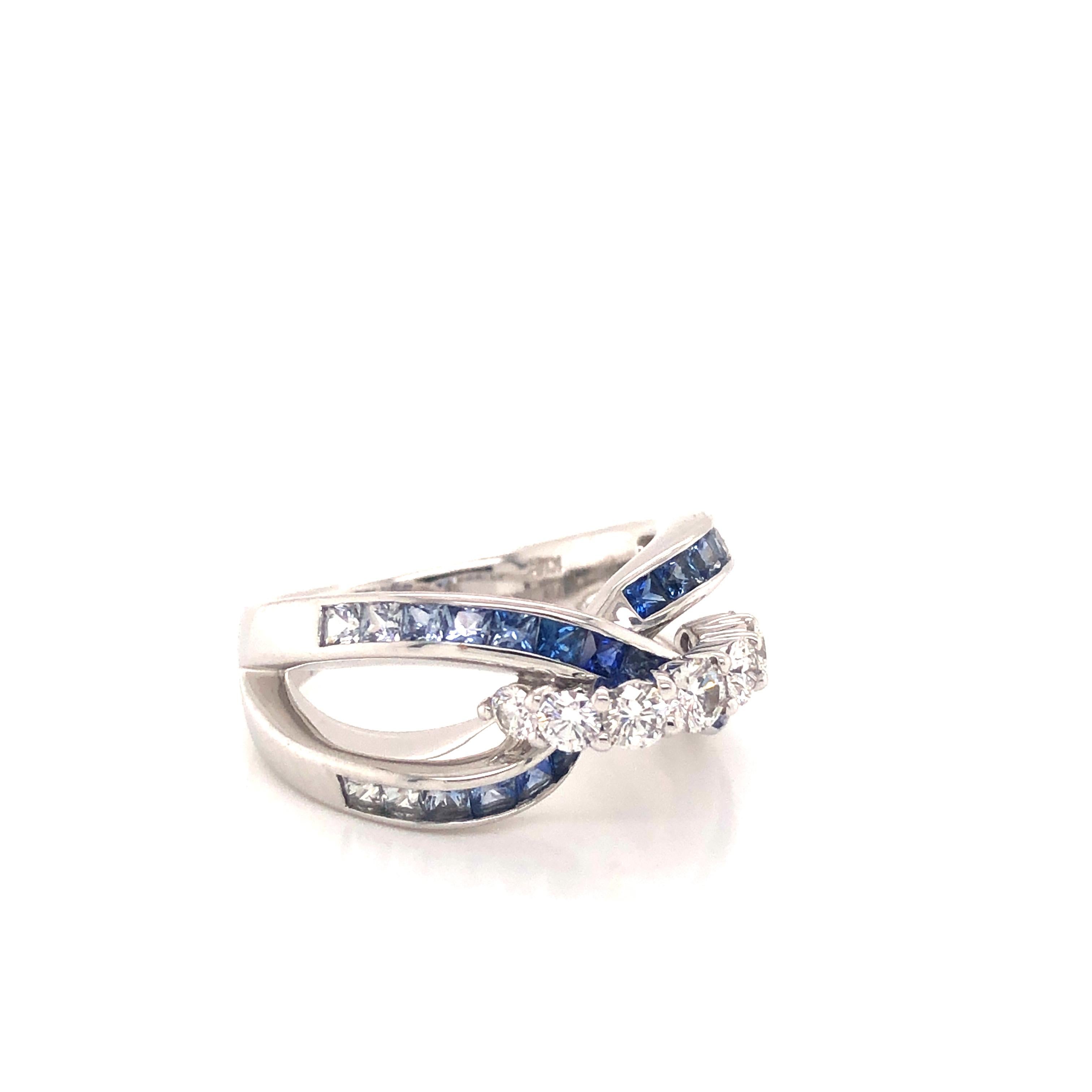 Gorgeous ring crafted in 18k white gold. This ring is crafted with a modern design as multi colored sapphires are set in a rainbow pattern of blue along the band of the ring. Starting with lighter shades of blue that continue to vivid blue colors at