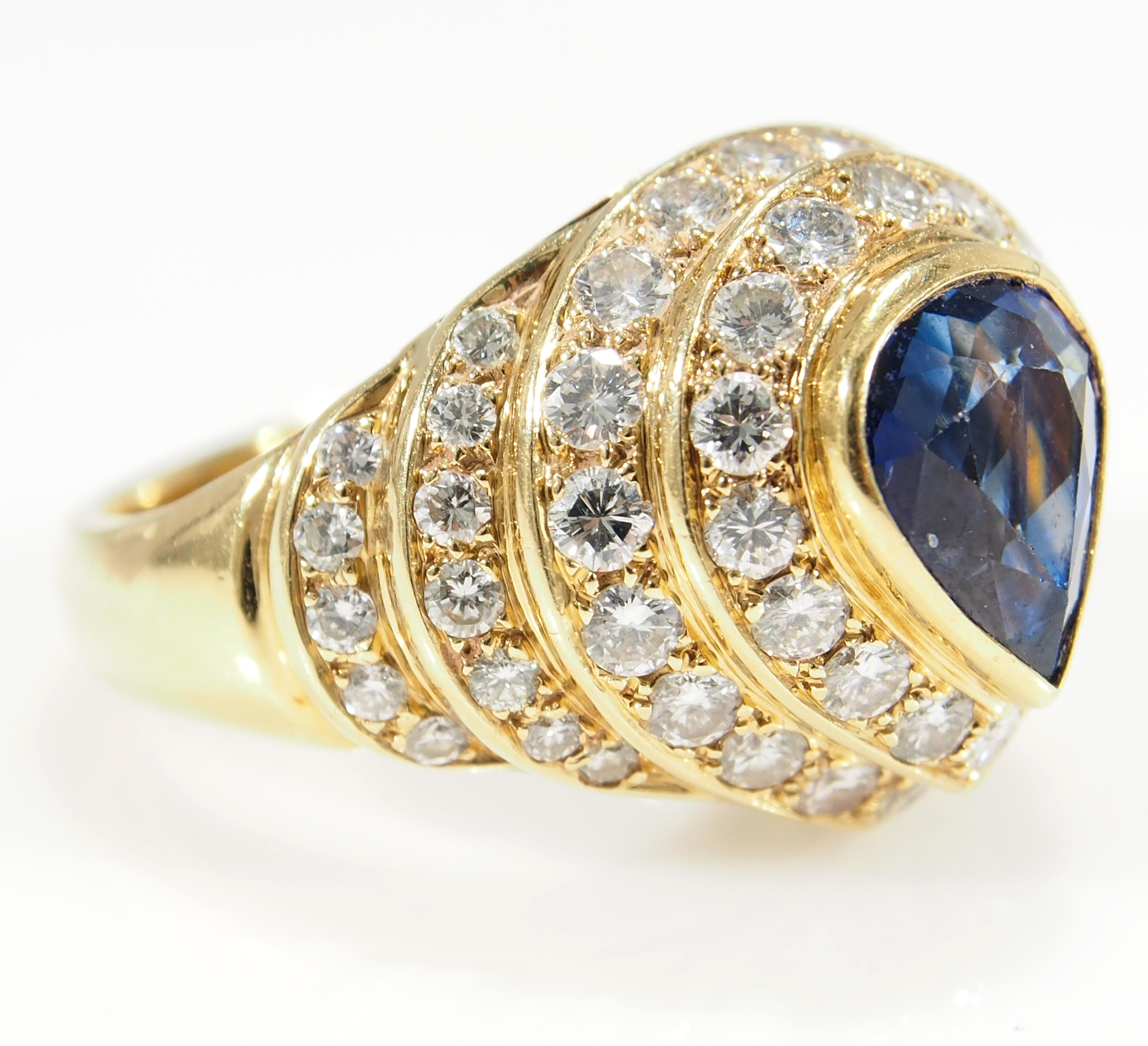 This is a lustrous 18K Yellow Gold Diamond and Sapphire Dome Ring. This sparkling Ring is fashioned with (1) Pear Shape Sapphire, approximately 2.00ct. as the center of the Dome accented by (4) Rows of concentric circles set with (57) Round