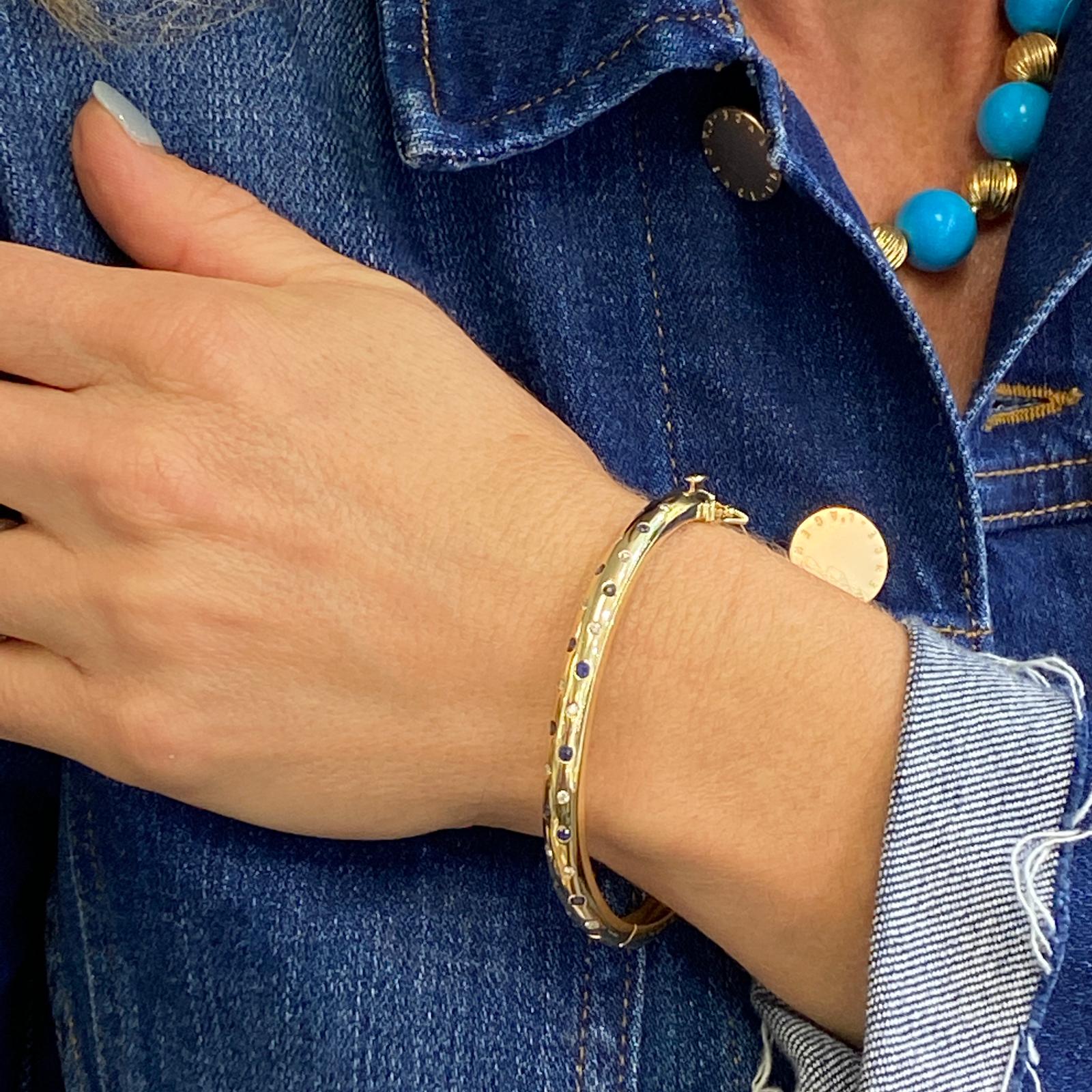 Armreif mit Diamanten und Saphiren aus 14 Karat Gelbgold. Der Armreif im Etoile-Stil enthält 14 runde Diamanten im Brillantschliff mit einem Gesamtgewicht von 0,28 Karat und 12 runde natürliche blaue Saphire. Der Armreif misst 2,5 Zoll im