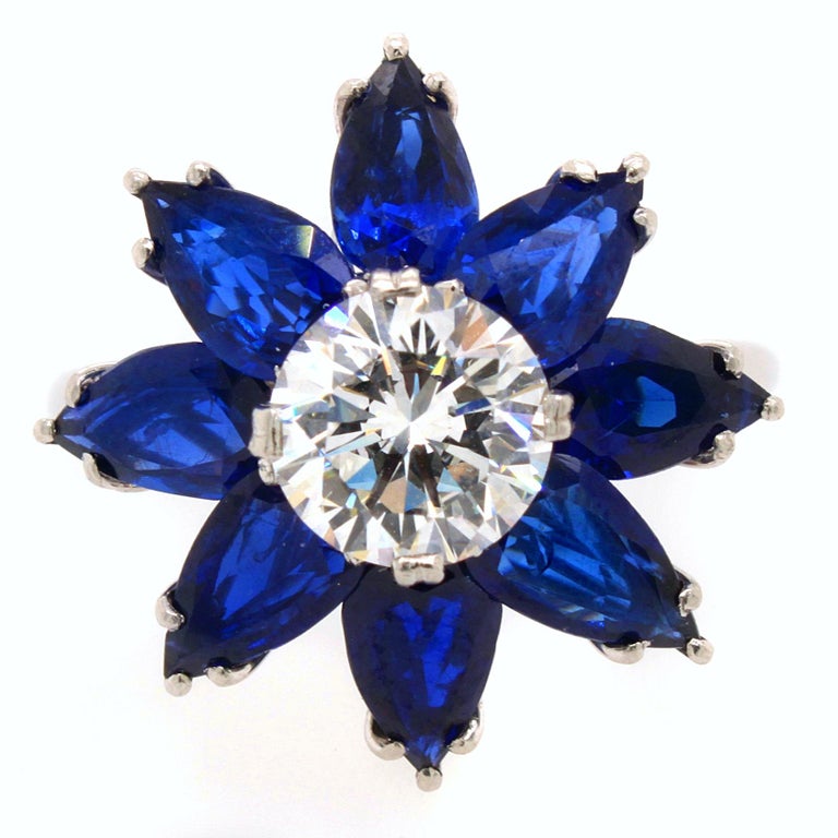 Lovely and chic flower cocktail ring made by the highly talented jeweller René Kern in the 1980s.
The center diamond weighs 1,05ct and is surrounded by pear shaped sapphires of approx. 3ct.
The diamond is colourless and of excellent quality (E/VVS1)