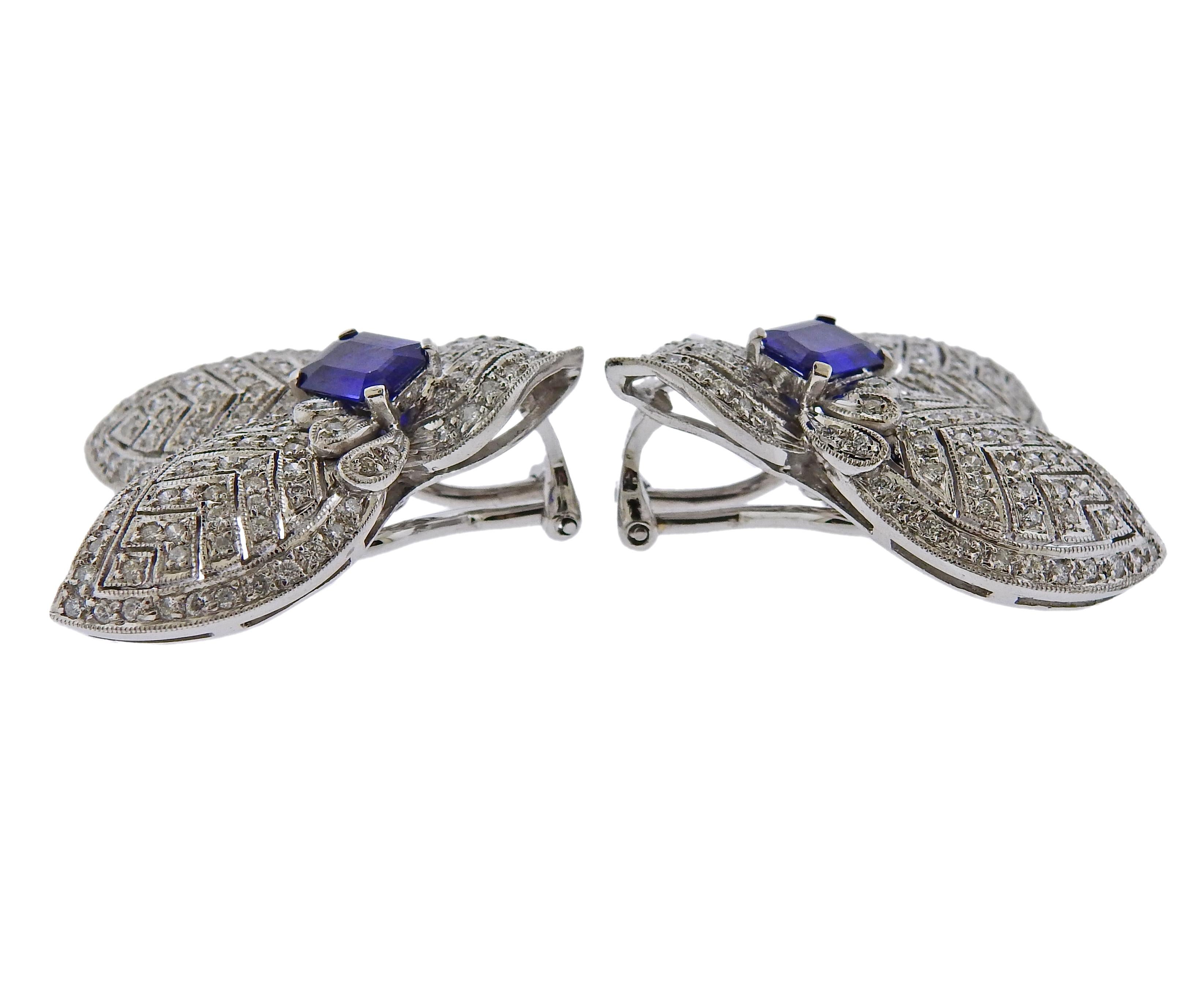 Pair of 18k white gold cocktail earrings, set with blue sapphires in the center, measuring approx. 7mm x 4.9mm, surrounded with approx. 0.70ctw in diamonds. Marked 750. Earrings measure 30mm x 25mm. Weigh 16.4 grams.