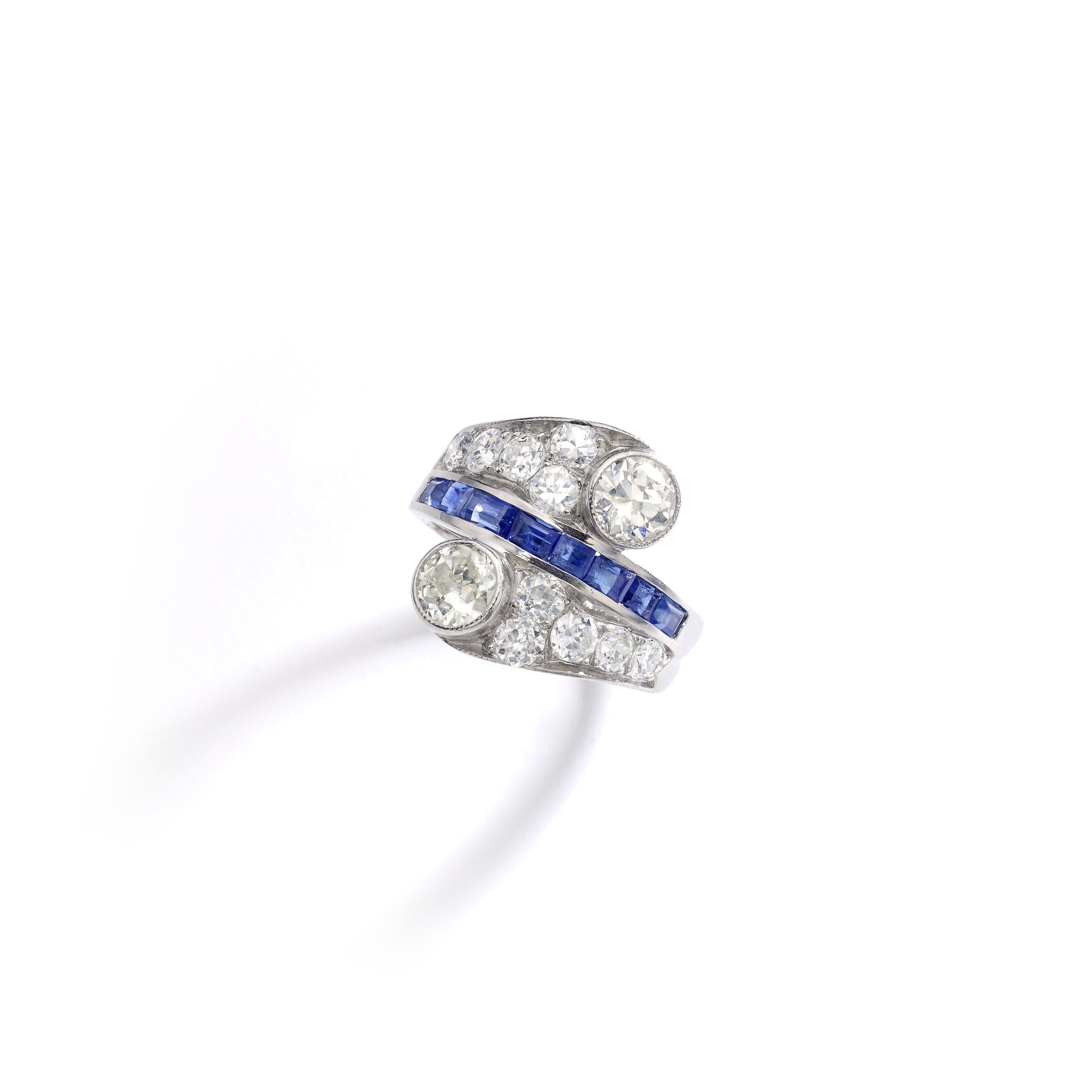 This 'Vous et Moi' crossover ring is all in platinum set by Old-mine cut diamond. 
Two diamonds are more significant and separated by a calibrated Blue Sapphire line.

Total Diamond weight: approximately 2.50 carats.
Ring size: 6 1/4.
Complimentary