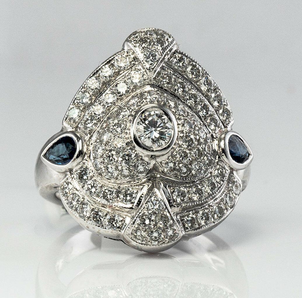 The ring is crafted in solid 14K White Gold and set with gorgeous diamonds and sapphires. The center bezel-set diamond is .20 carat. The face of the ring is encrusted with white and fiery diamonds. The diamonds are estimated to be VVS2 clarity and