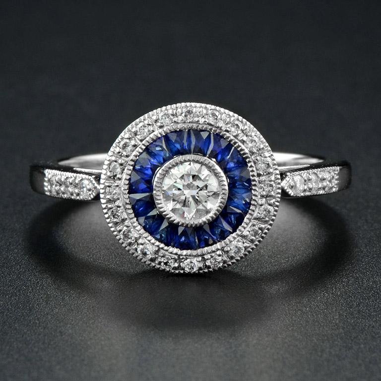 This Art-Deco engagement ring is completely spectacular! The vibrant color stone of blue sapphires are specialty cut to surround the excellent round brilliant cut center diamond, which is in a thin bezel with mil-grain detail. Crafted in