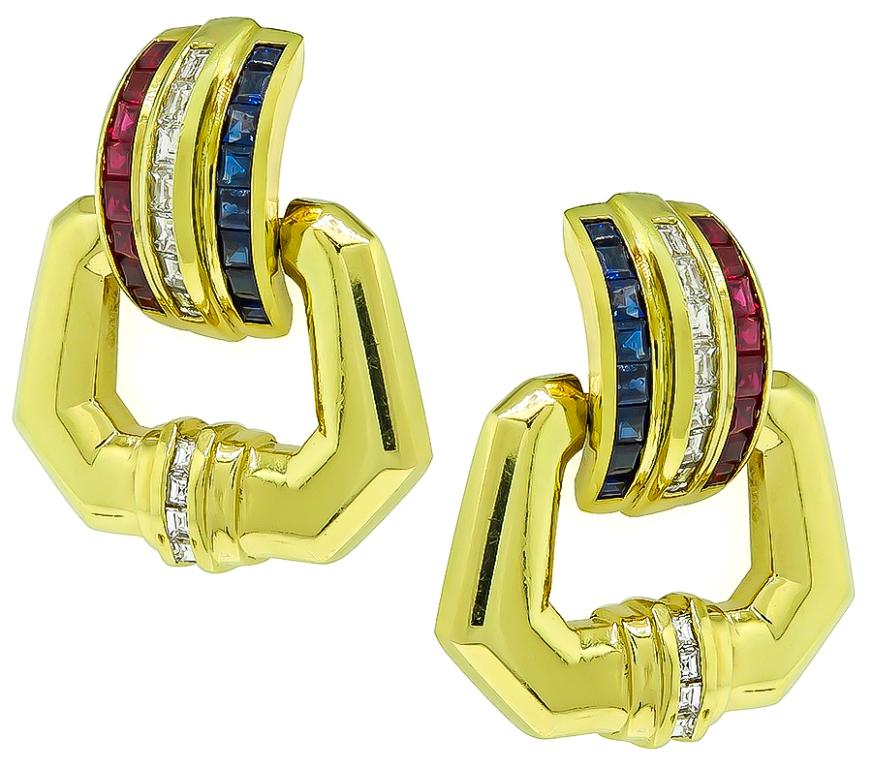 This elegant pair of 18k yellow gold door knocker earrings feature sparkling baguette cut diamonds that weigh approximately 0.80ct. graded F color with VS1 clarity. The diamonds are accentuated by lovely square cut rubies and sapphires that weigh