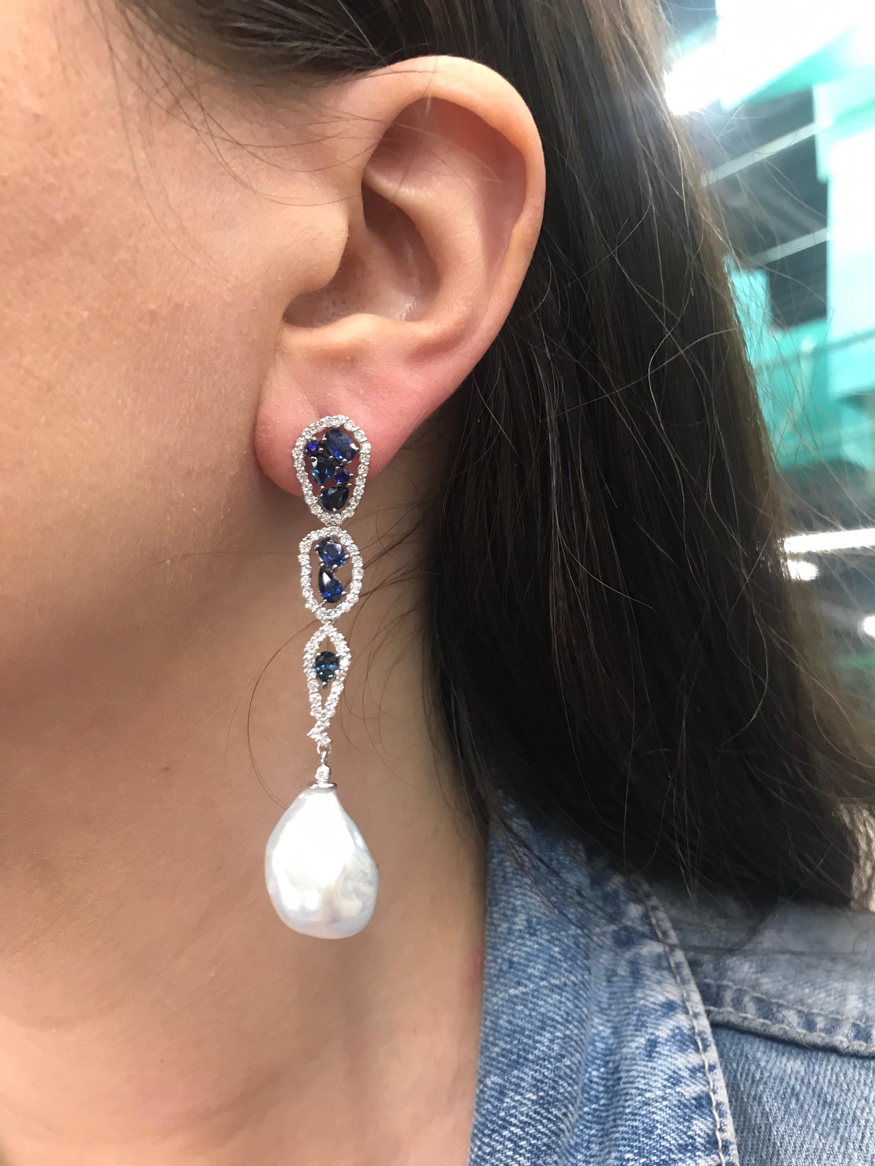 18K White gold drop earrings featuring 16 blue sapphires weighing 3.10 carats flanked with round brilliants weighing 1.28 carats and two South Sea Baroque Pearls measuring 13-14 mm. 