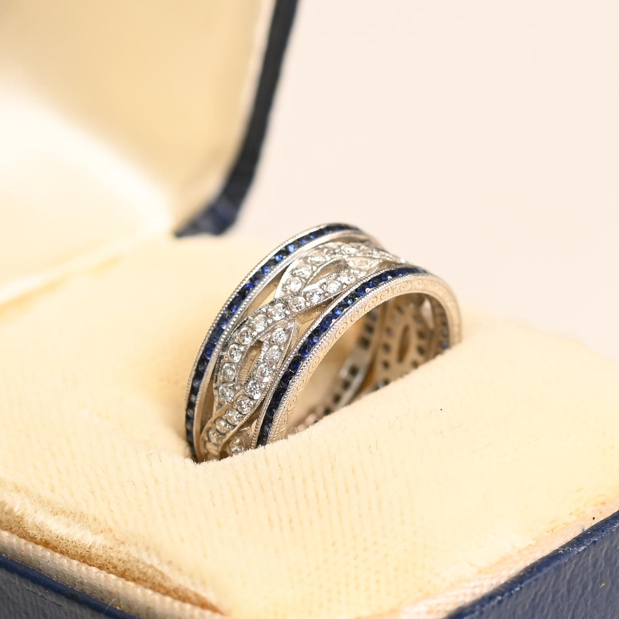 Dieser exquisite Platin-Ehering besticht durch sein filigranes Design mit einer atemberaubenden Kombination aus Diamanten und königsblauen Ceylon-Saphiren. Das Herzstück bilden zwei ineinander verschlungene Reihen von Diamanten im Brillantschliff,