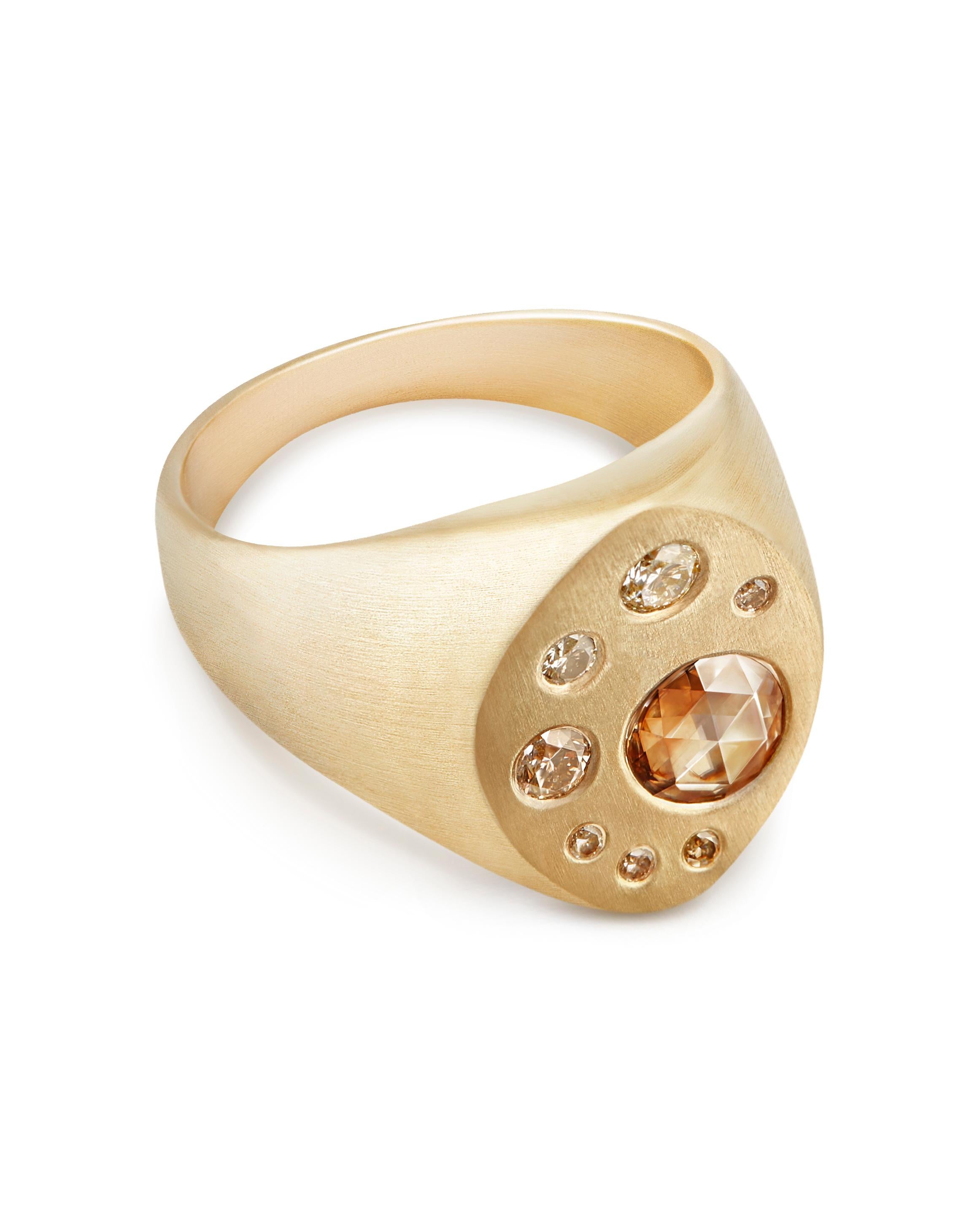 This contemporary take on the classic signet ring is crafted from solid 9-carat yellow gold and features eight diamonds ranging in size and color from pale champagne to cognac and a brushed finish to the gold.  The largest feature stone is a rustic