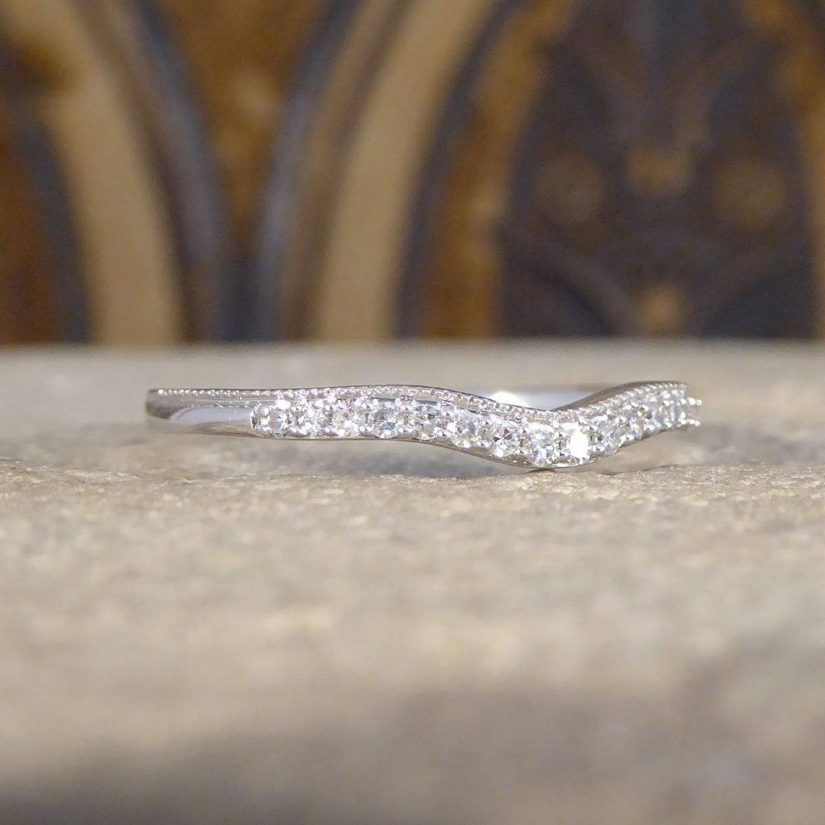 A lovely fine Diamond set ring. This ring features 16 small Diamond weighing a total of 0.10ct across the head of a beautiful 18ct White Gold ring with a slight curved wishbone with a milgrain edge on top. The shape of this ring is designed to sit