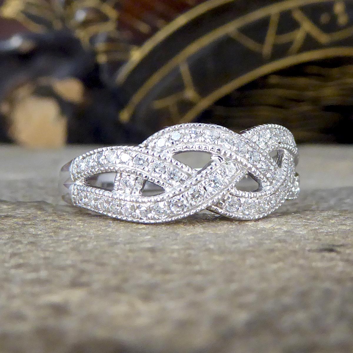 This ring is new and never worn. It features 49 Modern Brilliant Cut Diamonds all of equal size set in a channel with detailing formed to look like a Diamond set plait. The Diamonds are clear and bright with the plait weave spreading the full head