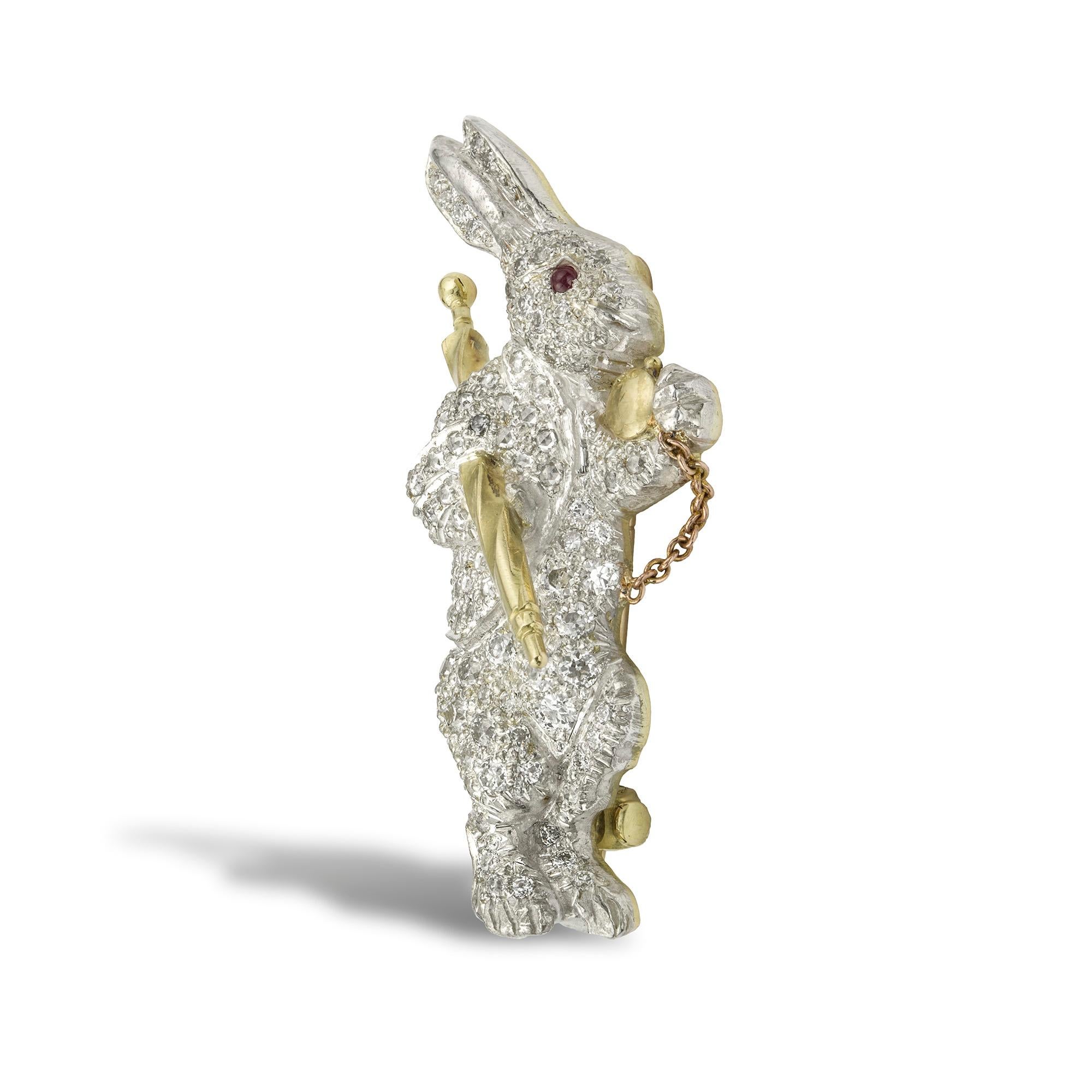 A diamond-set white rabbit brooch, the upright rabbit carrying an umbrella under his arm and a yellow gold pocket watch in his hand, set throughout with brilliant-cut diamonds, weighing a total of 1.10 carats, with a ruby eye, all set in silver to a