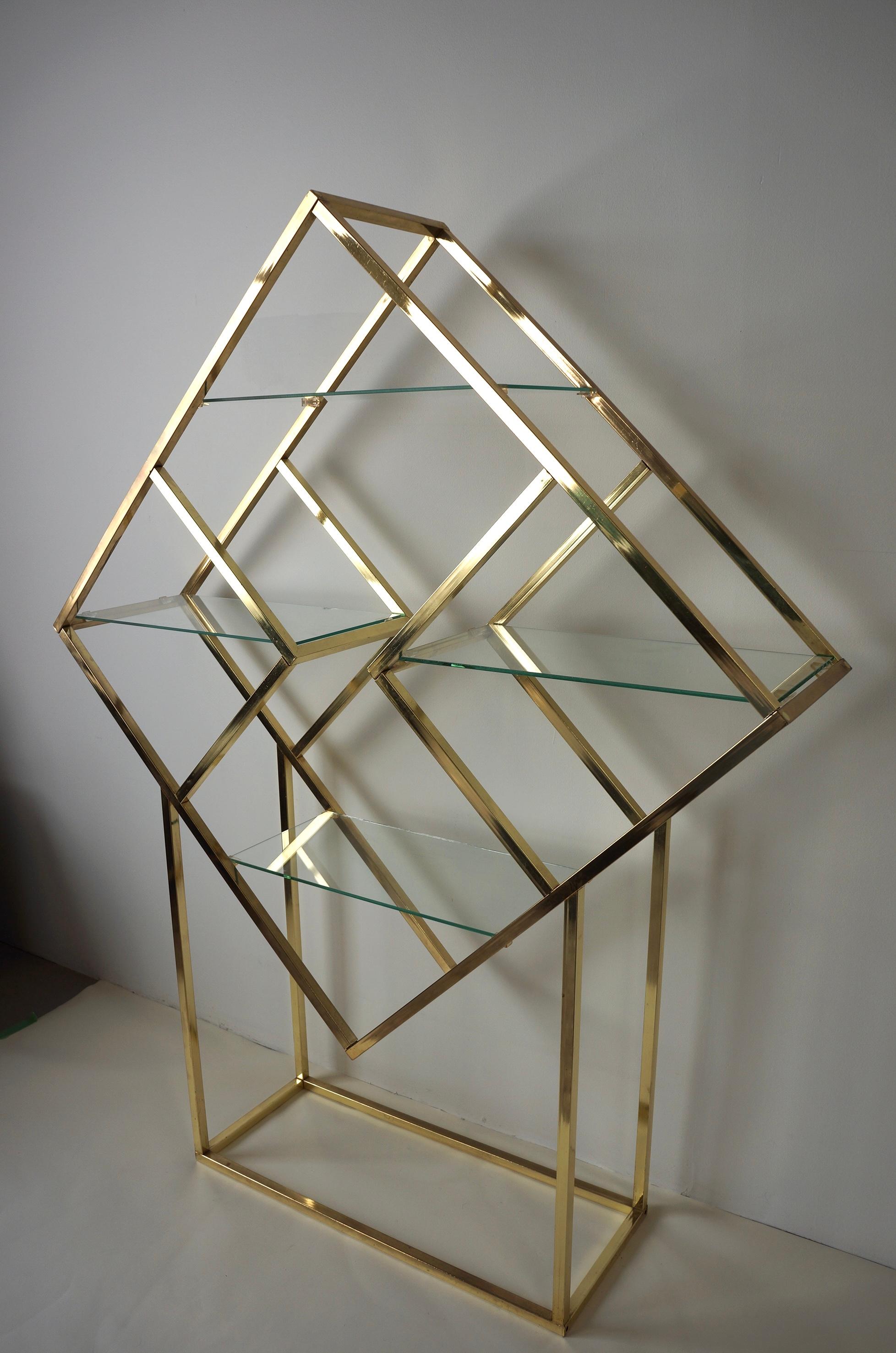 Diamond shaped Hollywood regency style brass plated shelf. It features 4 glass shelves that look like they’re floating. This timeless brass shelf would look gorgeous in any space as it’s a timeless piece.