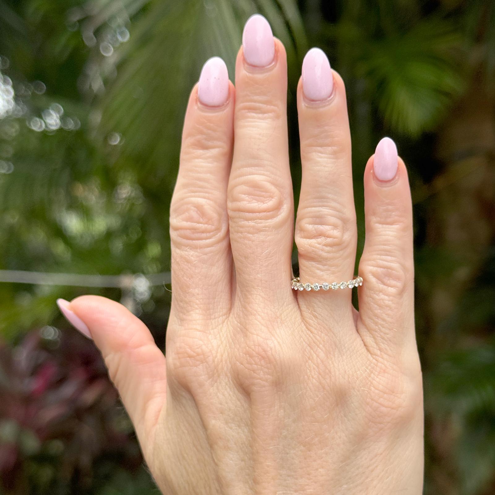 This timeless diamond band is crafted in 14 karat yellow gold and features 13 round brilliant-cut diamonds, totaling approximately 0.50 carats, graded G-H color and SI clarity. The stones are set in a classic shared prong design, allowing maximum