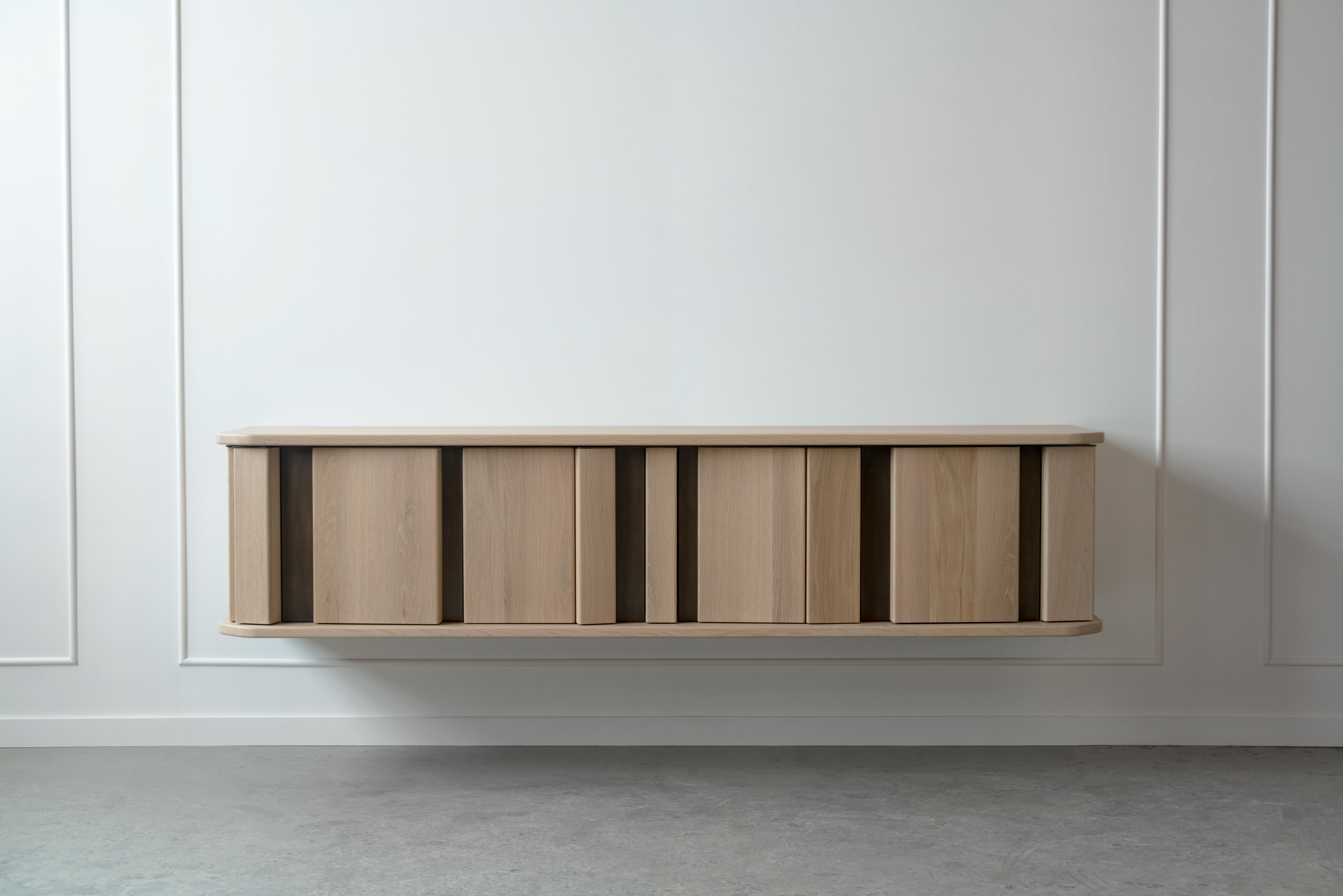 The diamond sideboard plays with different planes. A collection of rectangular columns placed at random angles and depths forms a facade interrupted by two thick horizontal planes of solid wood. This array of volumes serves as doors to a fully