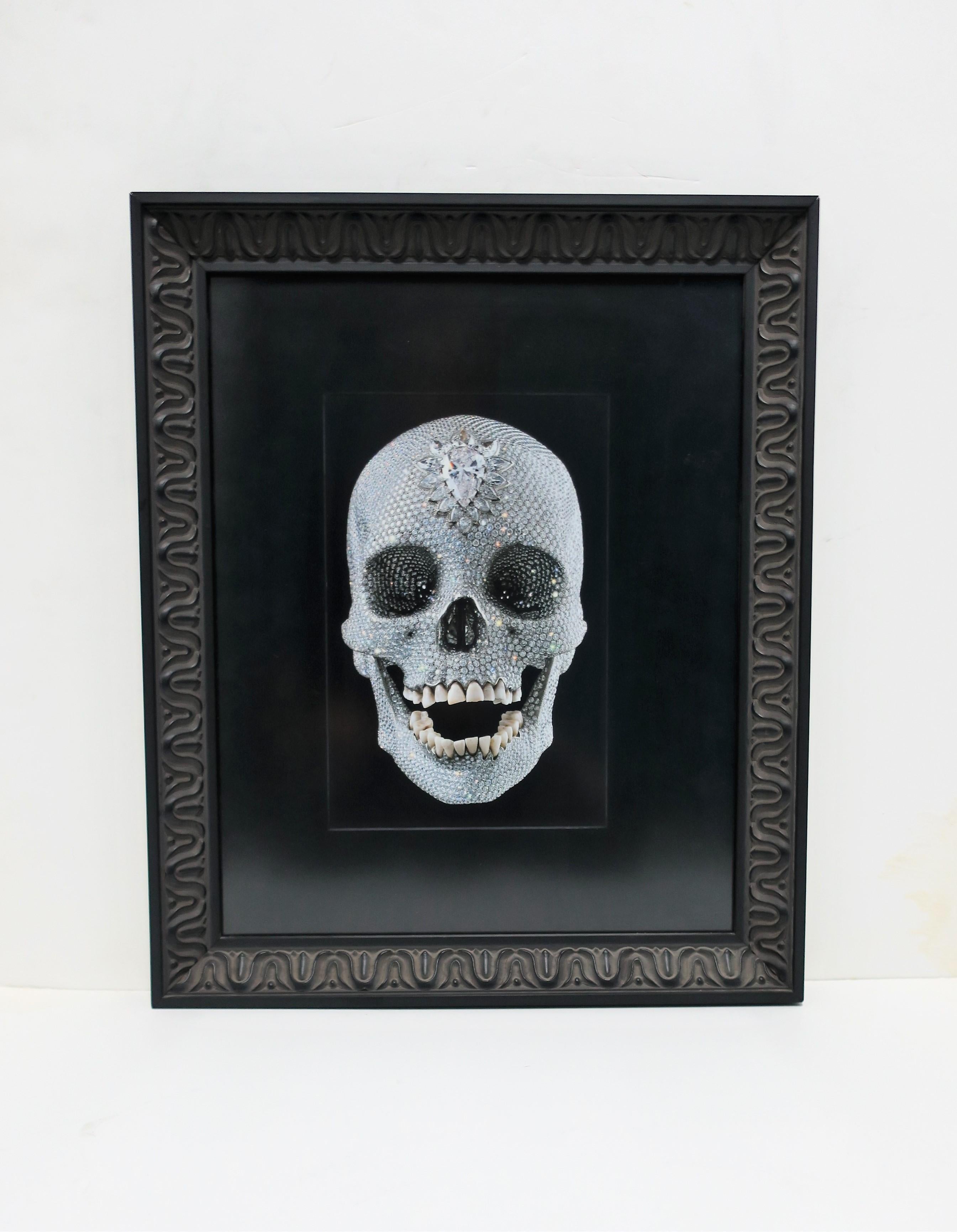 A beautiful image of a platinum and diamond skull with human teeth, titled, 'For the Love of God', a sculpture created by English artist, Damien Hirst, circa 2007. Photograph or art work, 'For the Love of God', is surrounded by black matte paper,