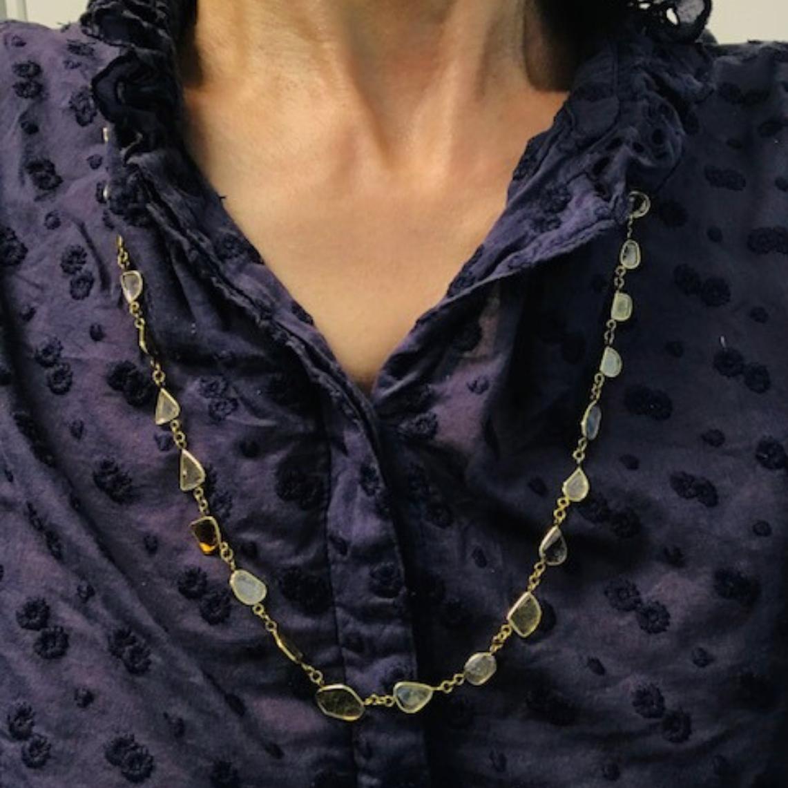 Ce collier en or 18 carats présente un arrangement organique de diamants gris, chacun serti dans une fine monture en or. Les diamants sont de forme irrégulière, ce qui confère à la pièce un aspect naturel et discret. D'un ton variant du gris pâle au