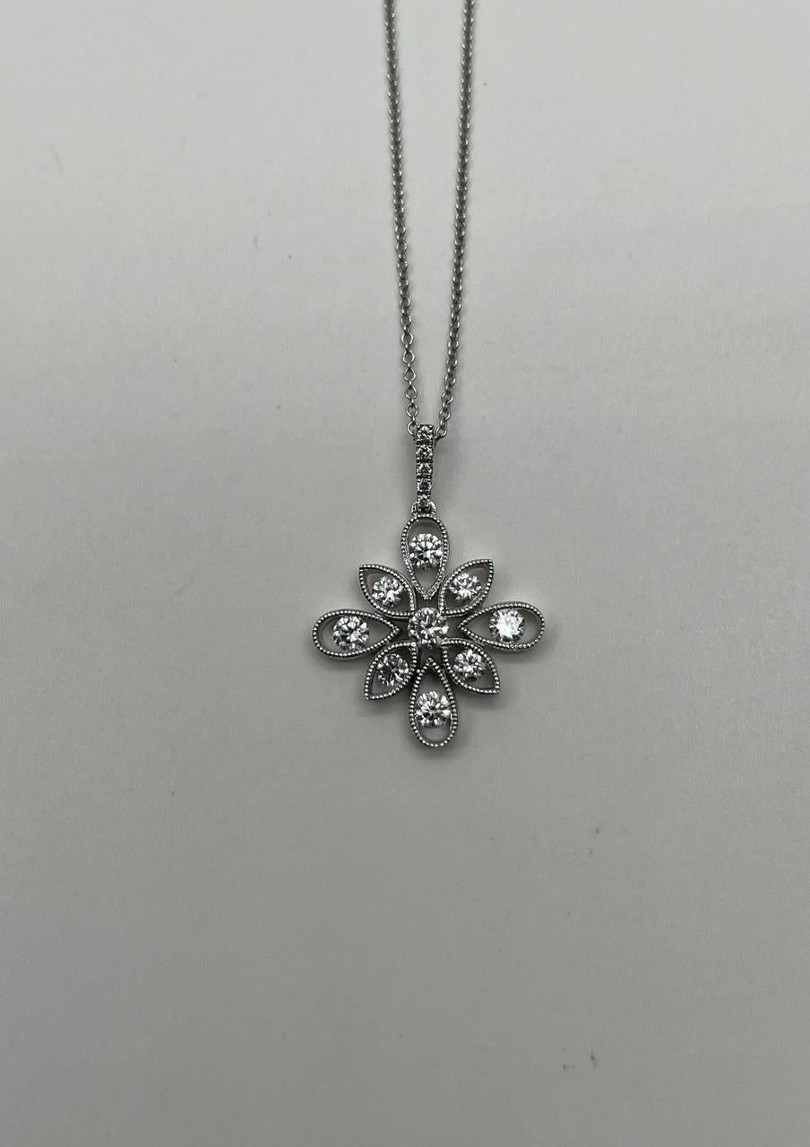 This exquisite necklace is crafted in 18k white gold. The pendant features a stunning floral design with white diamonds set in each petal, creating a captivating sparkle. The intricate detailing around each stone enhances its brilliance. 
Metal: 18k