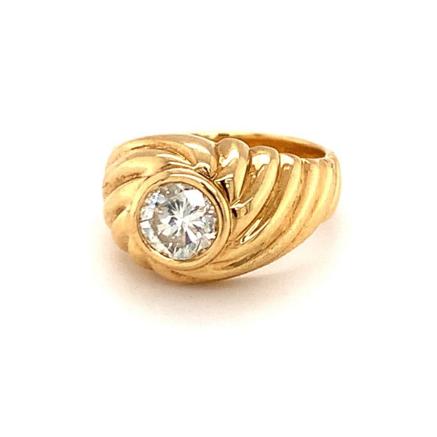 One diamond solitaire 18K yellow gold ring centering one bezel set, round brilliant cut diamond weighing approximately 1.10 ct. with K-L color and SI-2 clarity. With ribbed high polish gold mount.

Chunky, robust, gleaming.

Additional