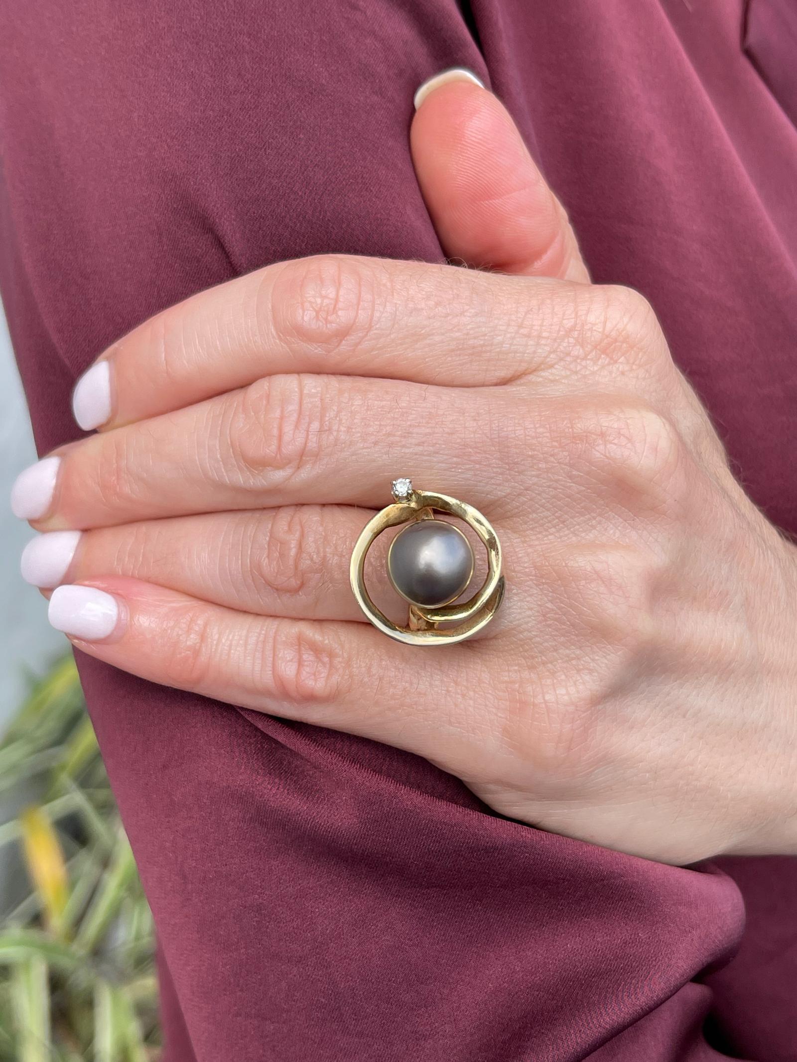 South Sea pearl and diamond ring handcrafted in 14 karat yellow gold. The ring features an 11.5mm South Sea pearl and a round brilliant cut diamond weighing approximately .06 carats. The open circular ring measures 20 x 20mm on top and is currently