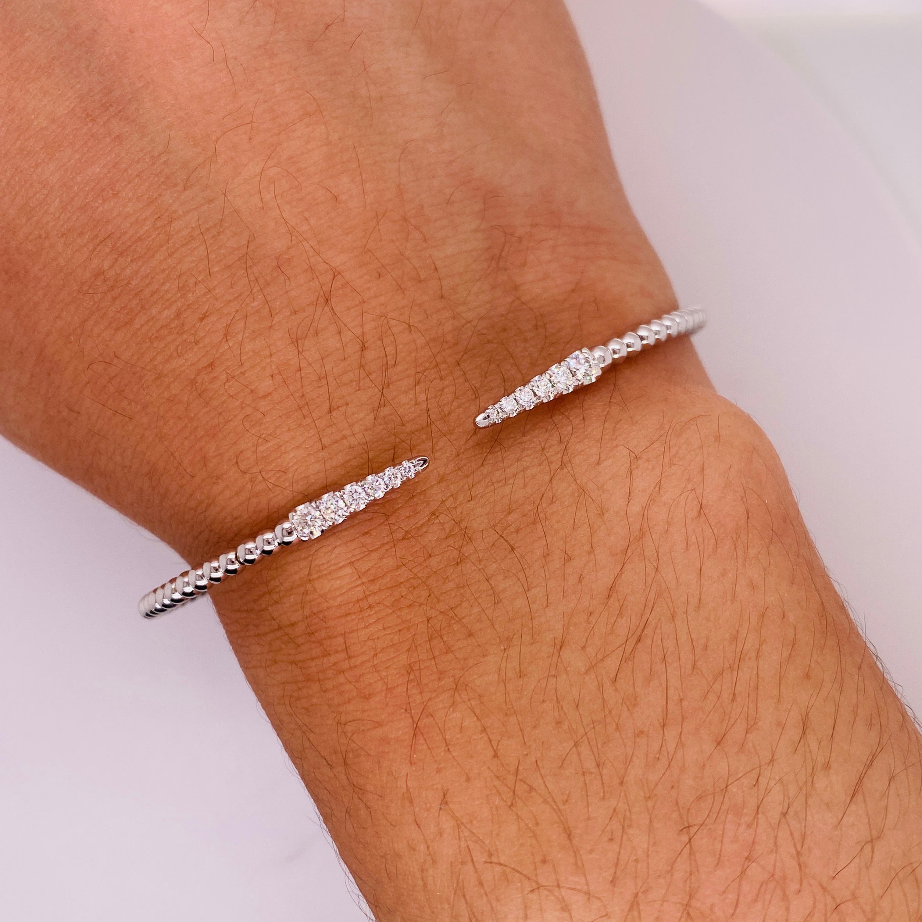 This bracelet overturns standard cuff bracelet design by making the cuff opening the focal point! Tapering round brilliant diamonds shine bright along the sleek and edgy spikes. Beautifully slender and comfortable, this low-profile bangle bracelet