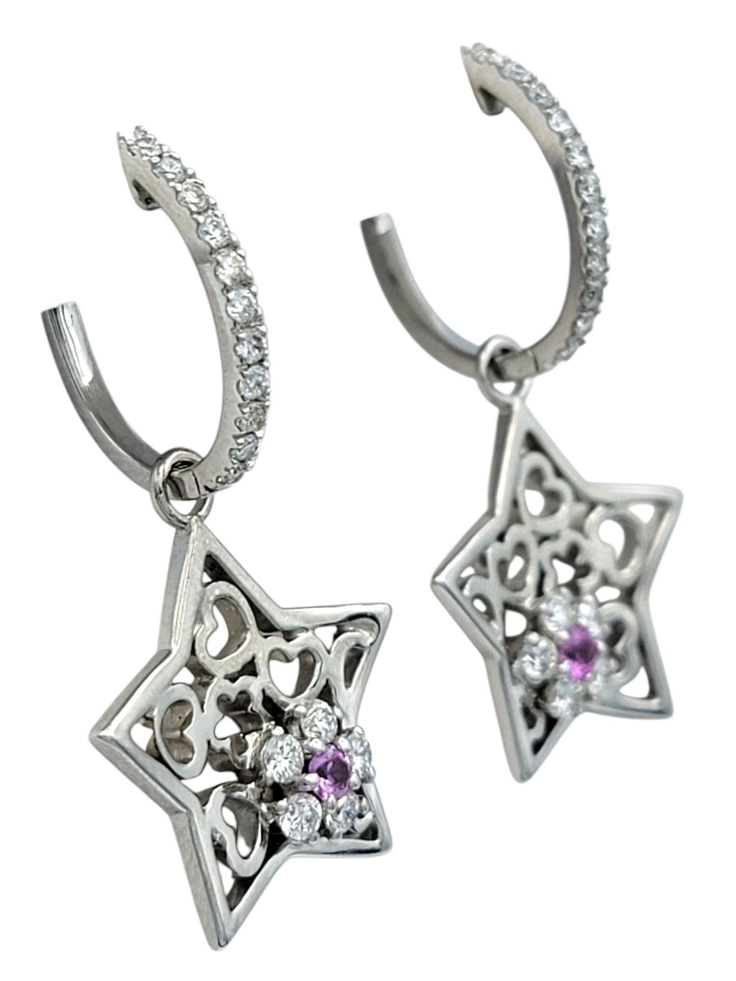 These whimsical earrings bring together charm and sparkle with their playful star motifs and fine craftsmanship. The star-shaped charms dangle gracefully from diamond-accented hoops, each adorned with a natural pink sapphire at the center, offering