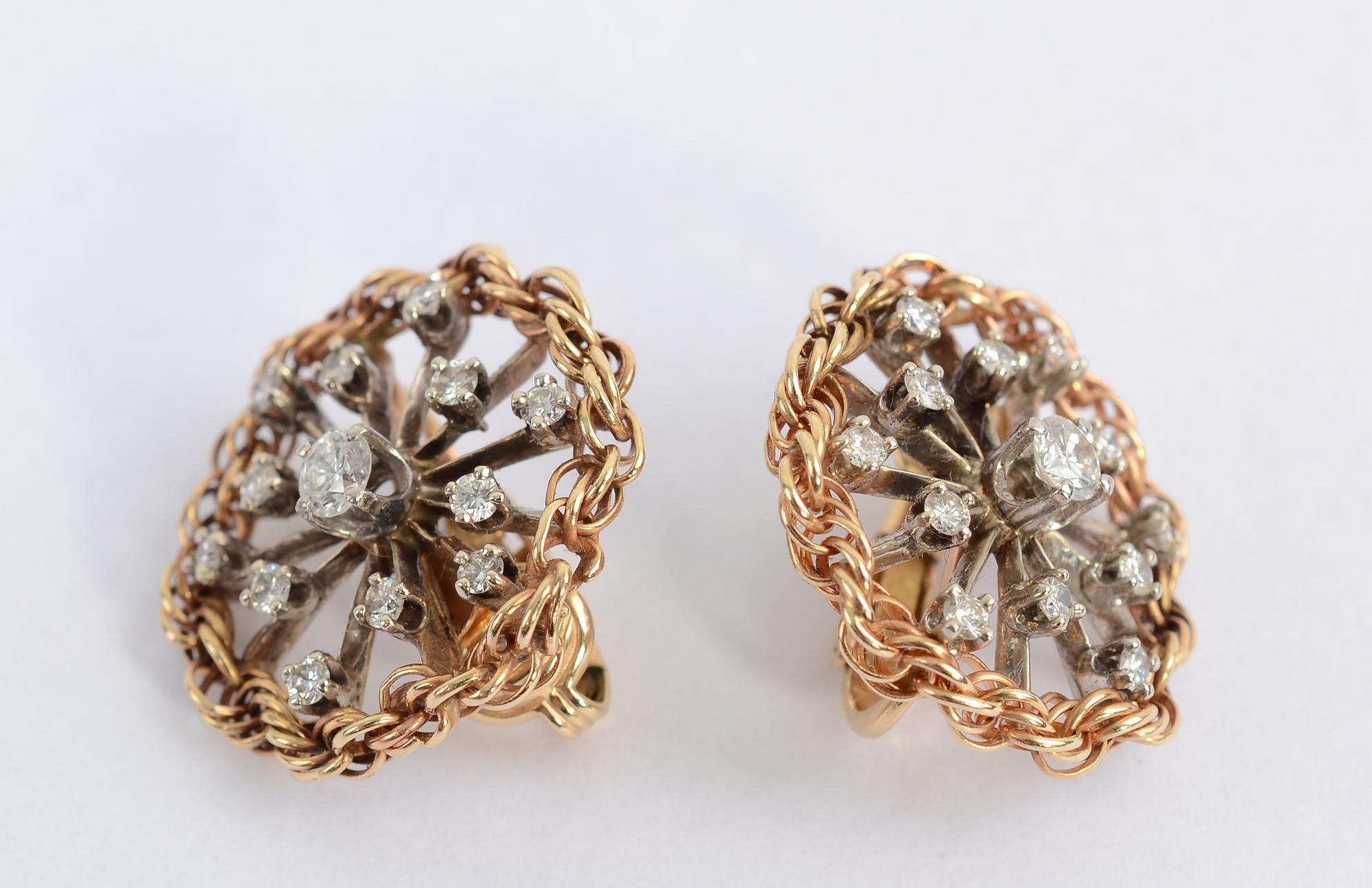 Eleven satellite diamonds surround a fifth of a carat diamond in these quintessentially 1950's earrings. The diamonds and spokes are white gold while the twisted roping around the stones is yellow gold. The earrings have clip backs. They measure 7/8