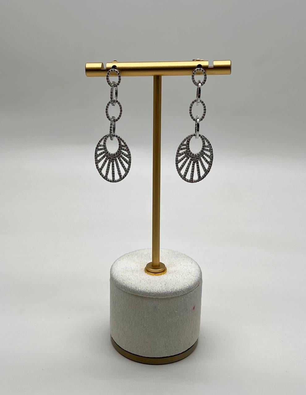 These contemporary earrings  feature a striking design with circular elements. Each earring showcases a series of interlinked rings leading to a fan-like motif, adorned with intricate detailing diamond accents. 14K White Gold. 1.53 CTW Diamonds.