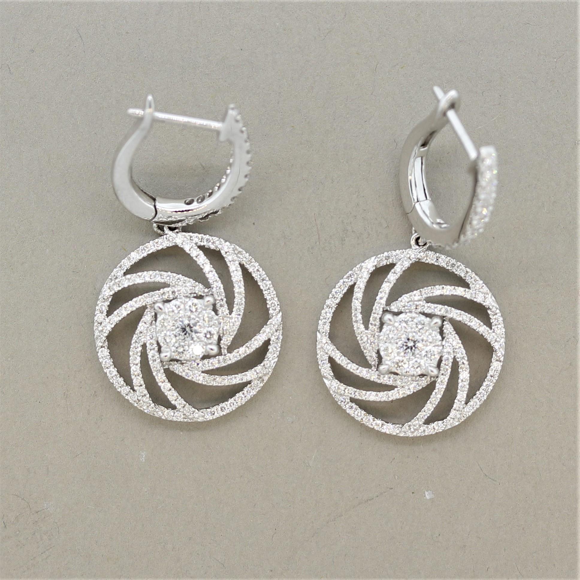 A stylish and classy pair of earrings featuring 1.08 carats of round brilliant cut diamonds. They are set in a swirl pattern around the earrings as well as in a small cluster in the center of the earrings. Made in 18k white gold and ready to be