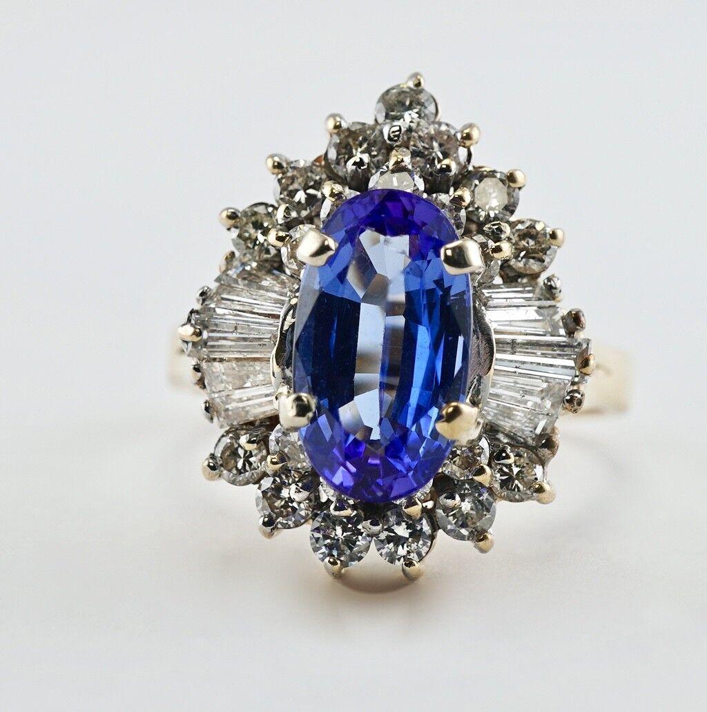 This beautiful estate ring is finely crafted in solid 14K Yellow gold and set with genuine Earth mined Tanzanite and diamonds. The center gem measures 11mm x 6mm (1.52 carats), and this is a very clean gem of great intensity and strong brilliance.