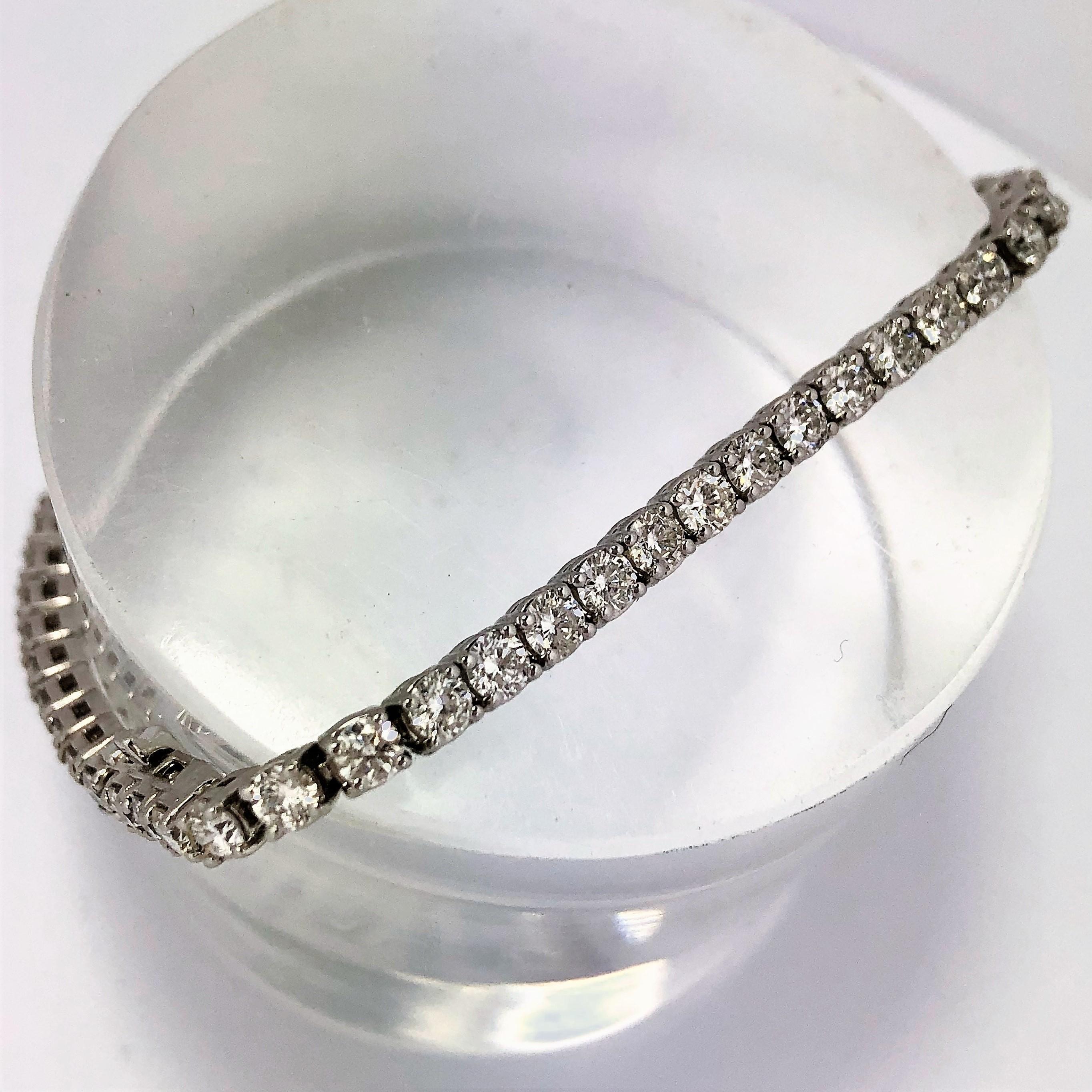 A traditional 18K White Gold Diamond Tennis Bracelet set with 55 round brilliant cut diamonds, set into 4 prong heads, weighing an approximate total of 5.44CT of overall G/H Color and VS1-VS2 Clarity. The beautifully matched, fine quality diamonds