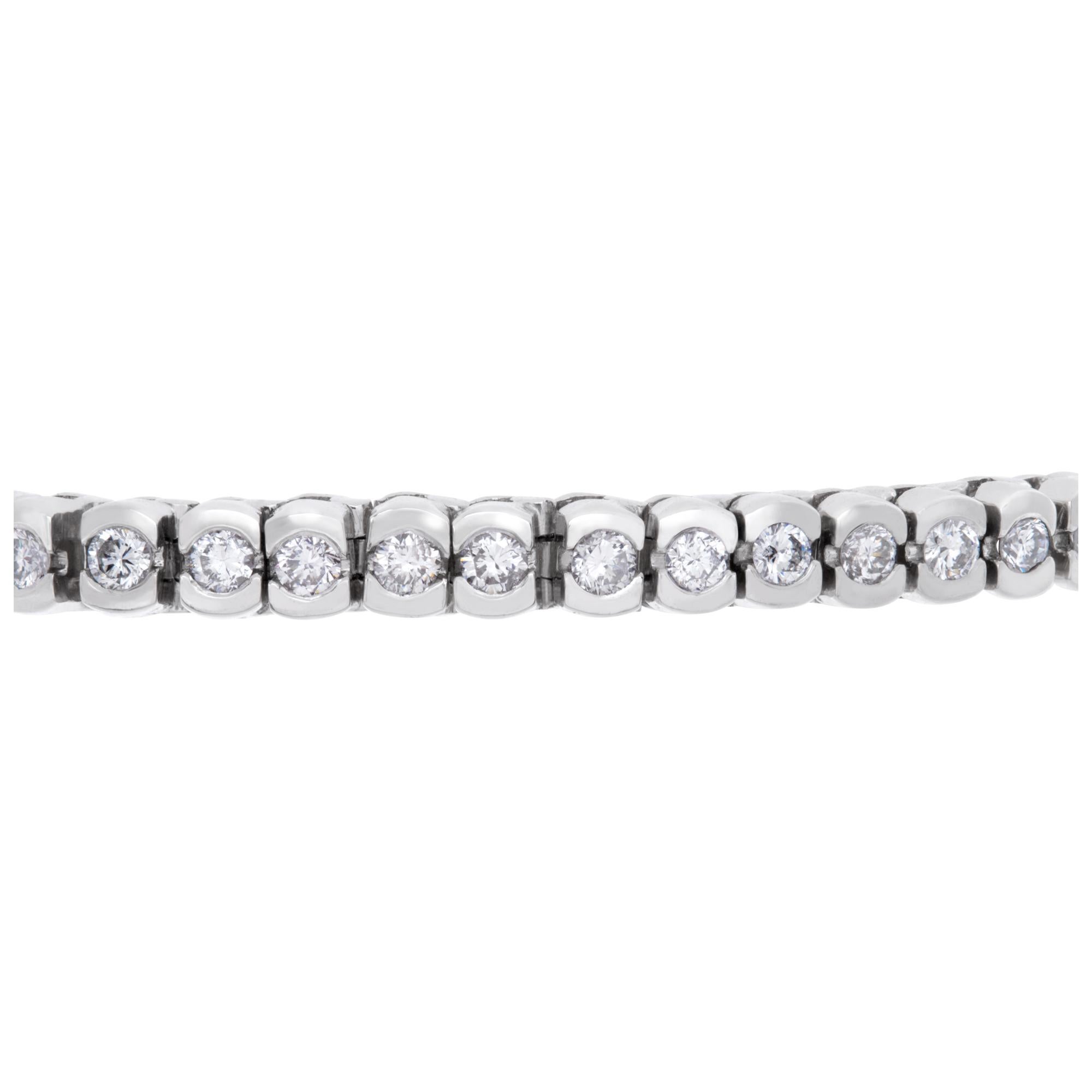 Diamond tennis bracelet in platinum with approximately 6 carats in round cut bezel set diamonds (G-H Color, VS1-VS2 Clarity). Bracelet has security clasp with chain. Length 7.5'', width 4mm.
