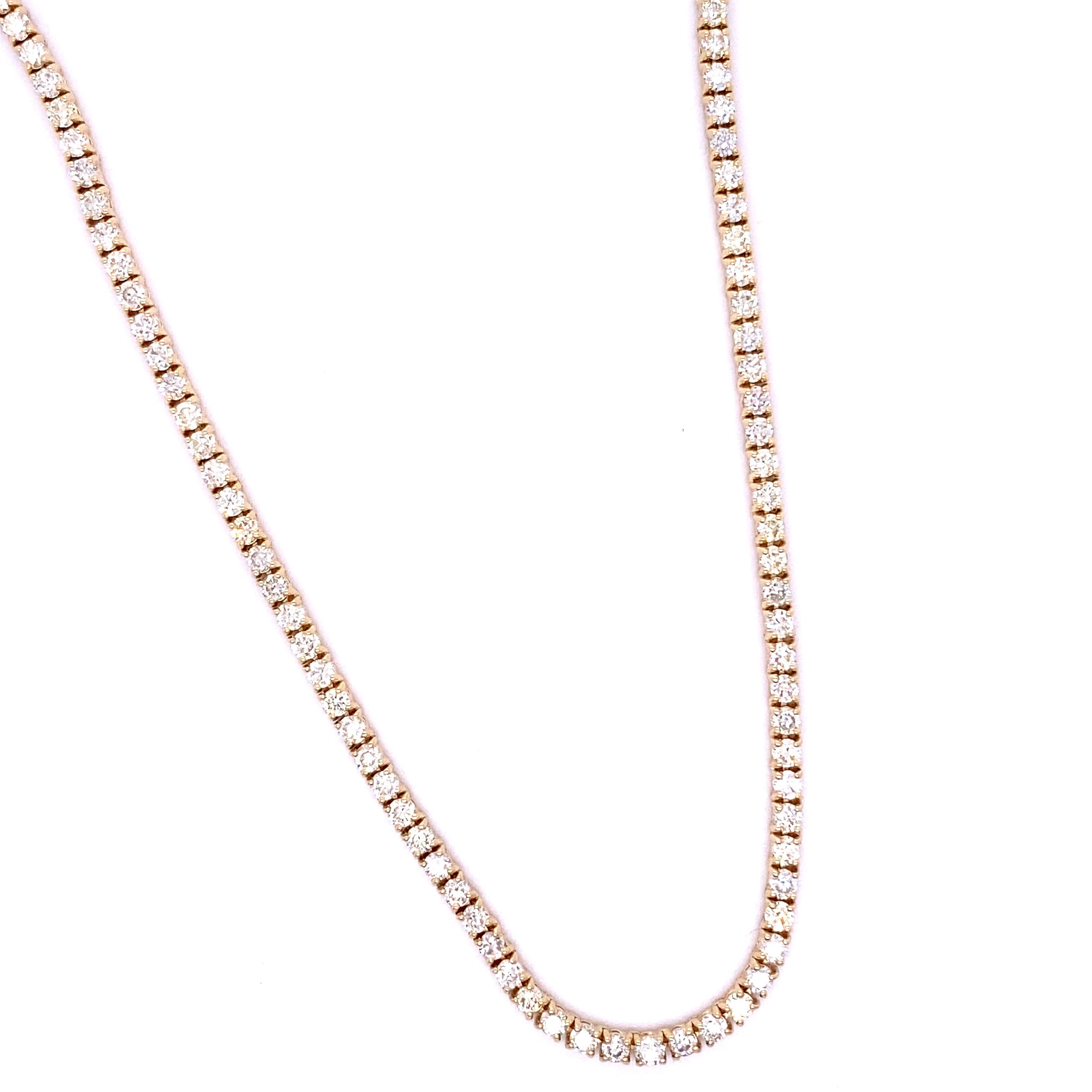 This tennis necklace features round brilliant cut diamonds in a prong setting. It is crafted from 18K yellow gold and has a total diamond weight of 7.30 carats.