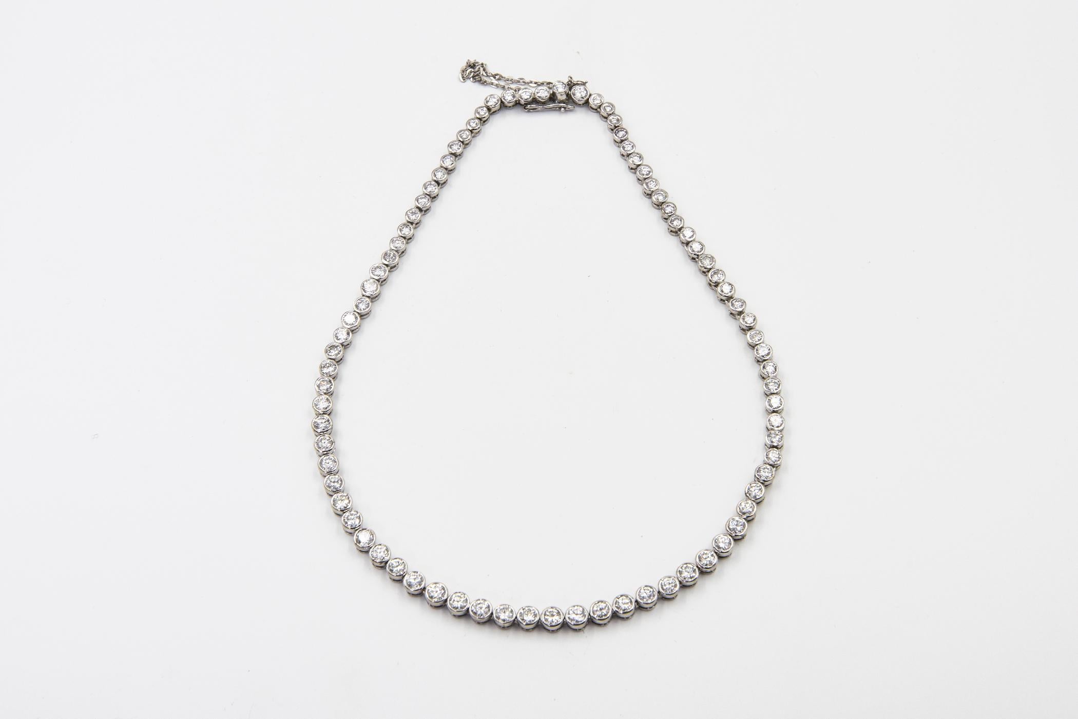 Collana tennis con diamanti naturali graduati montati in oro bianco 14k.  Ci sono 80 diamanti incastonati. Ha un peso totale di circa 9 carati di diamanti.  La chiusura è a pulsante con catena di sicurezza.  Questa collana è solo più corta della