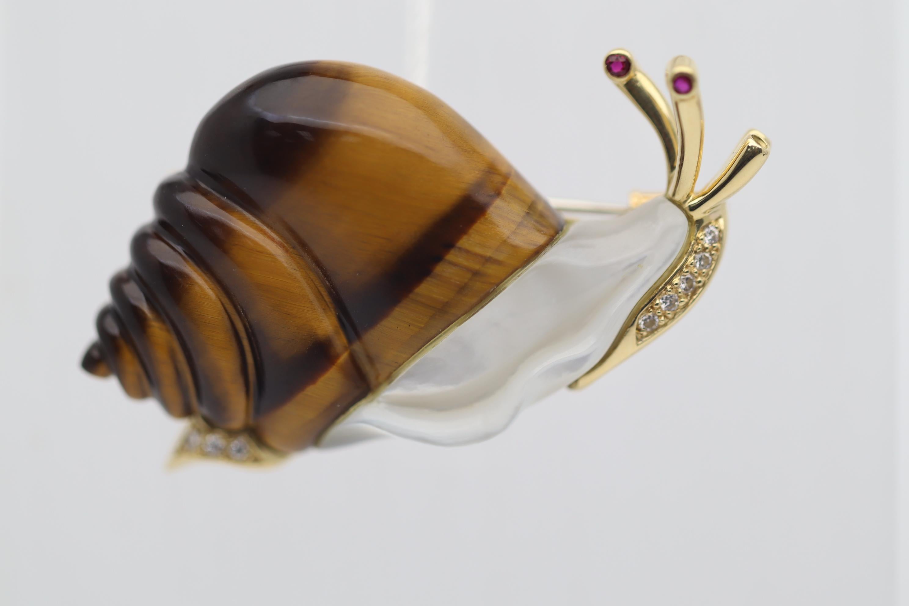 The most sweet and loving snail you will ever see! Made with a hand-carved tigers eye shell and a mother-of-pearl body, light rolls across the piece for added realism. It is framed and finished in 18k yellow gold with diamond set on its face and