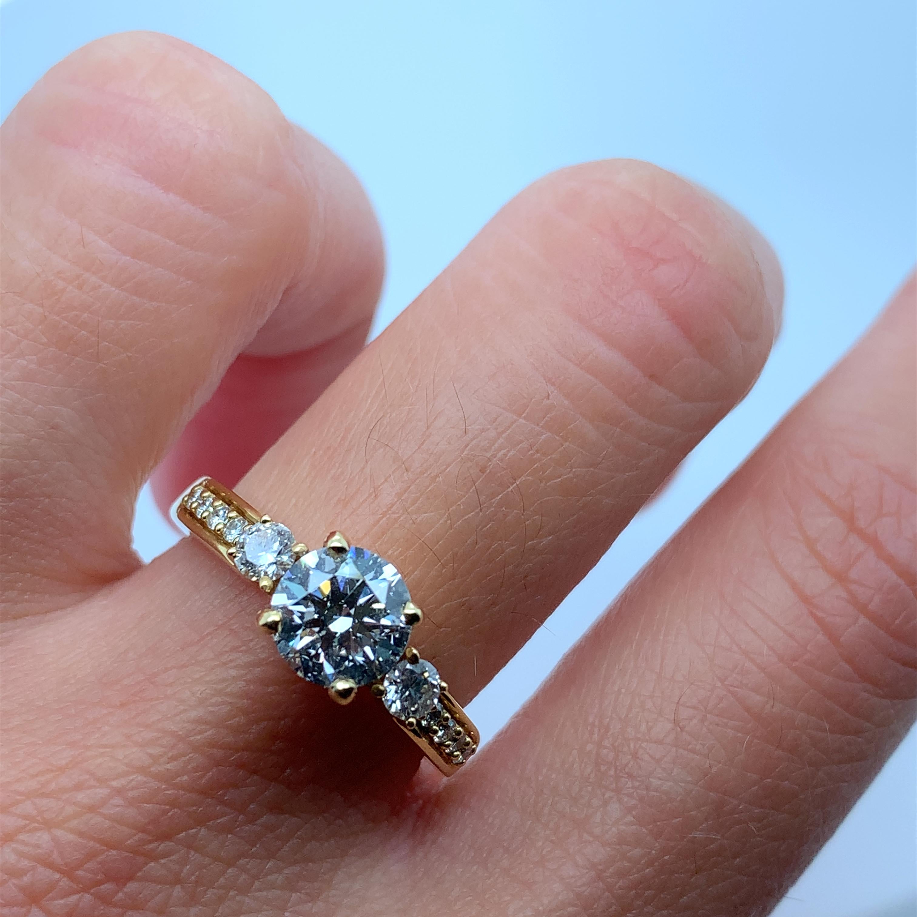 This stunning engagement ring is a must-have for any bride-to-be looking for a timeless and elegant piece of jewellery. Crafted with 18k yellow gold, this ring features a beautiful round diamond with a total weight of 1.31ct. The diamond is graded