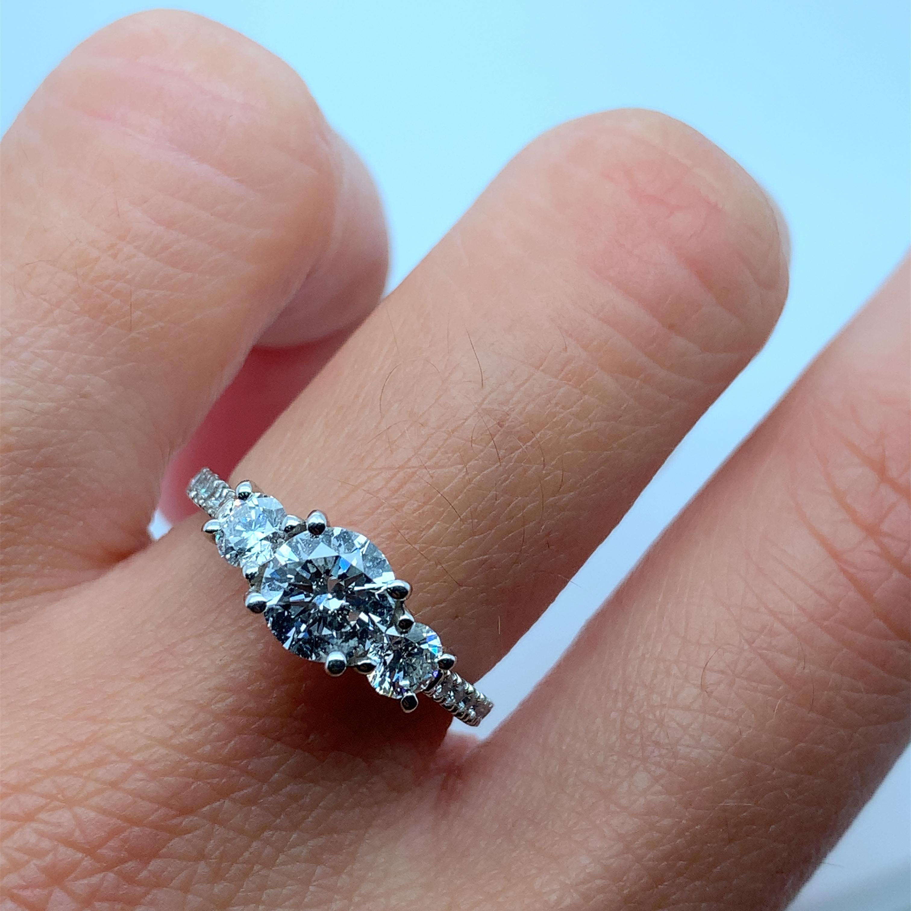 This stunning platinum engagement ring from Trilogy features a trio of beautiful round diamonds with a total carat weight of 1.46ct. The diamonds are set in a classic three-stone style, with a band width of 2-2.5mm. Beautiful classic trilogy