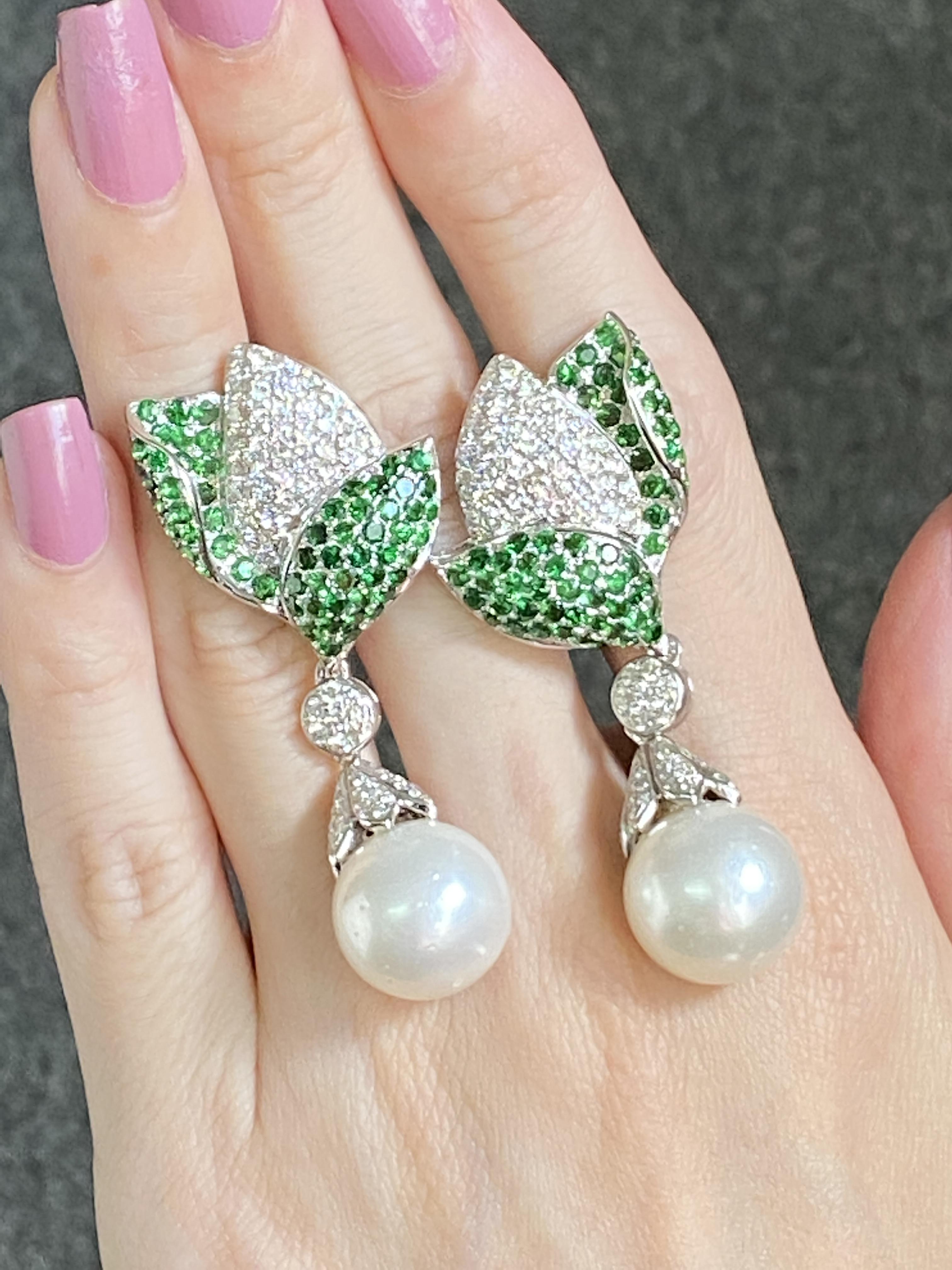 Make a statement with this beautiful pair of earrings! South Sea pearls dangling from 18K White Gold petals, studded with White Diamond and Tsavorite. The earrings are currently 2 inches long, and come with a push-pull backing.
Please message us for