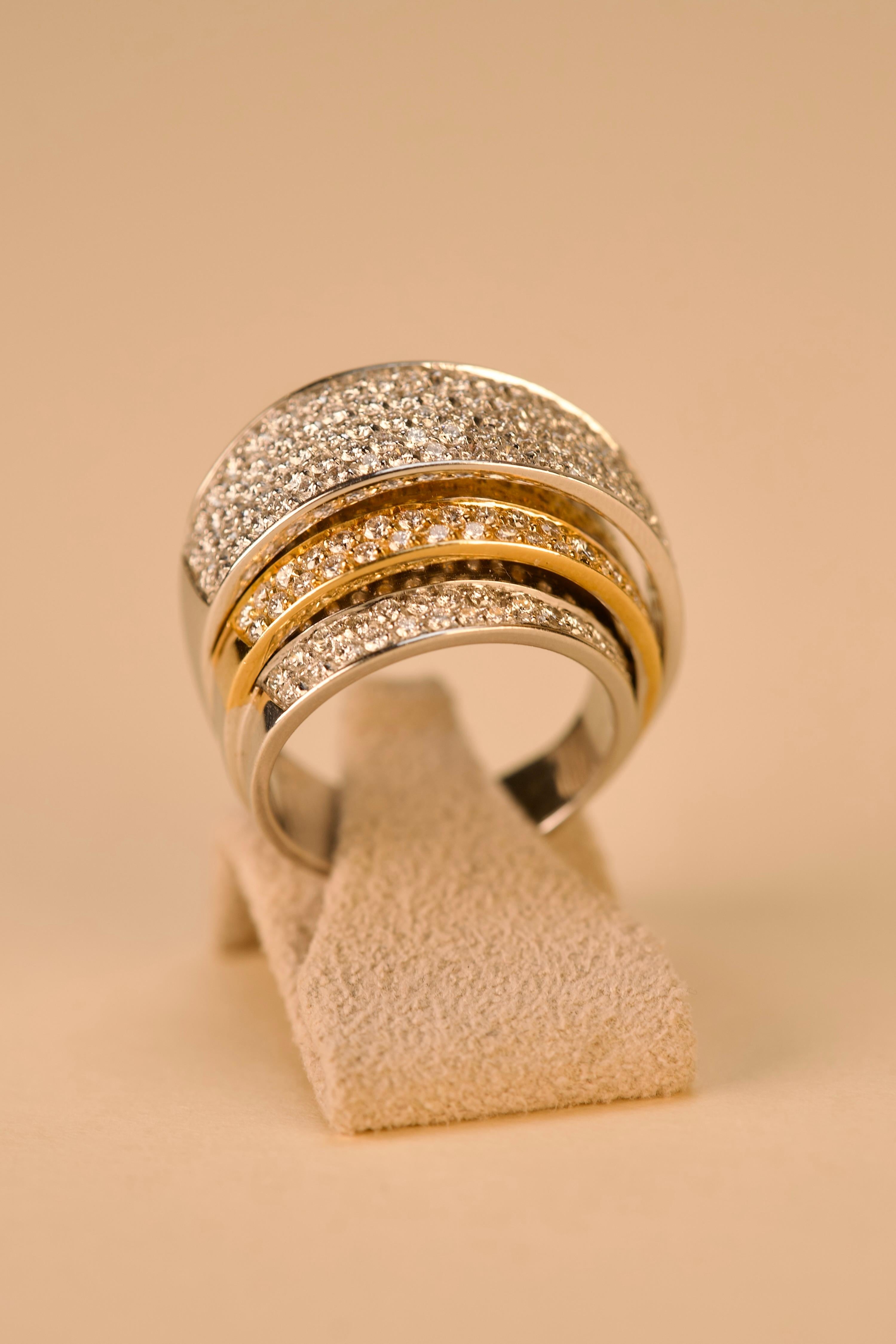 Dieser zweifarbige Goldring mit Diamanten ist aus 18-karätigem Gold gefertigt und mit einer skulpturalen dreistufigen Struktur versehen, die mit Volumen, Kontrast und Licht spielt. Die unterste und oberste Ebene ist aus Weißgold gefertigt und bildet