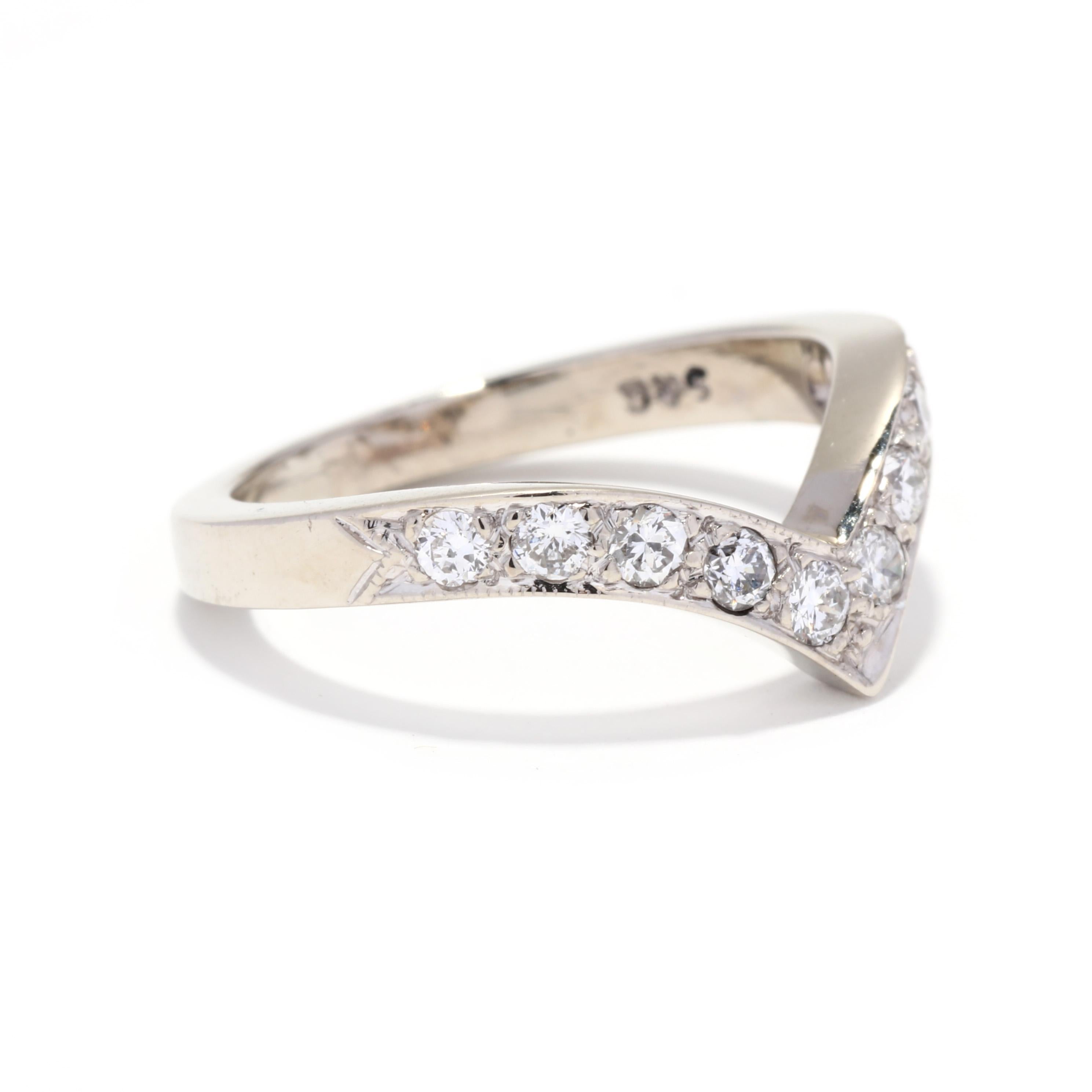 A vintage 14 karat white gold diamond V ring. This stackable ring features a curved V form with pavé set round brilliant cut diamonds weighing approximately .30 total carats and with a tapered band. Please note that one diamond has a small chip but