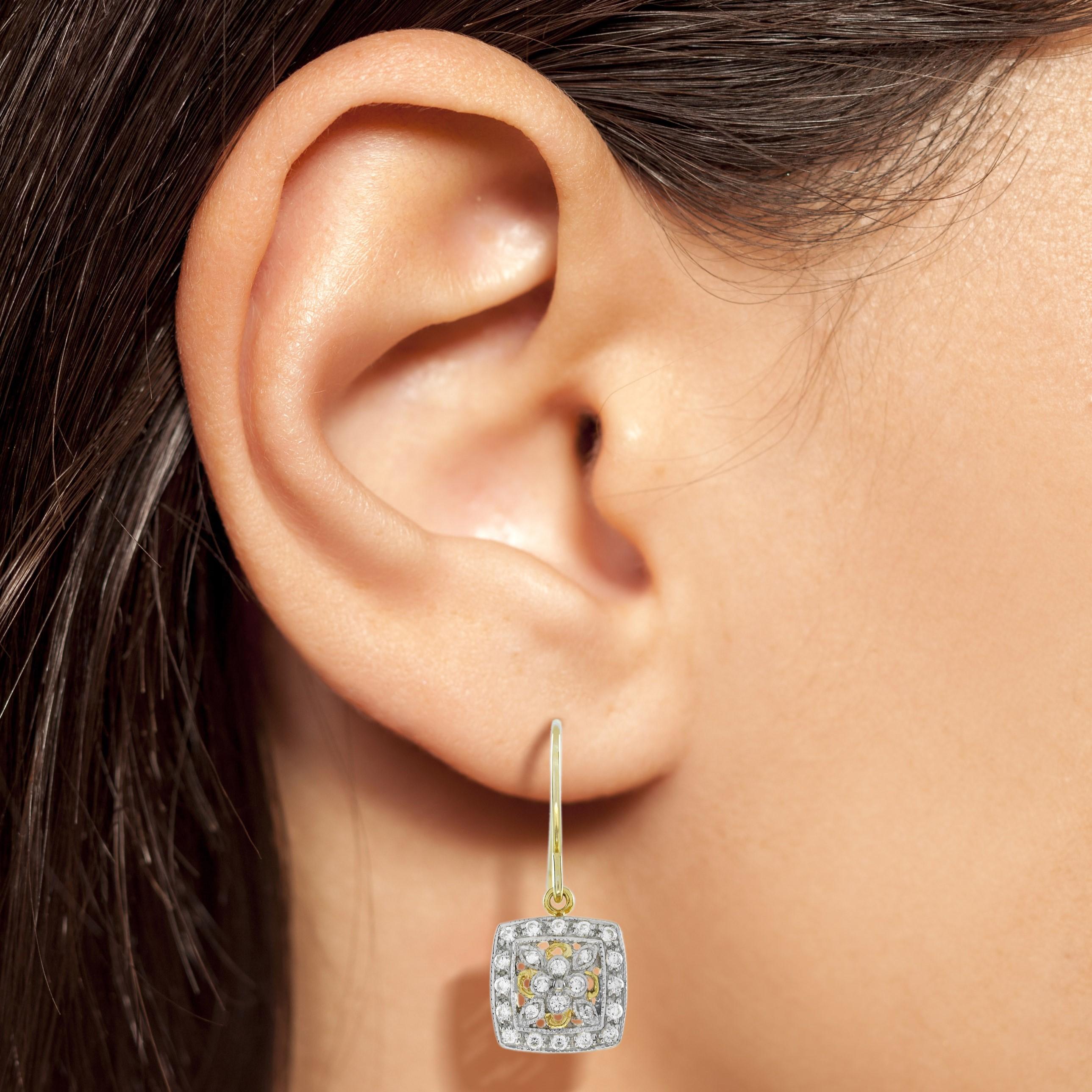 Glittery antique style earrings crafted in two-tone gold. With 48 round diamonds completely encrusting the earrings face, this piece is truly a work of art on the lobes. The square frame of diamonds surrounds the center picture of floral in an