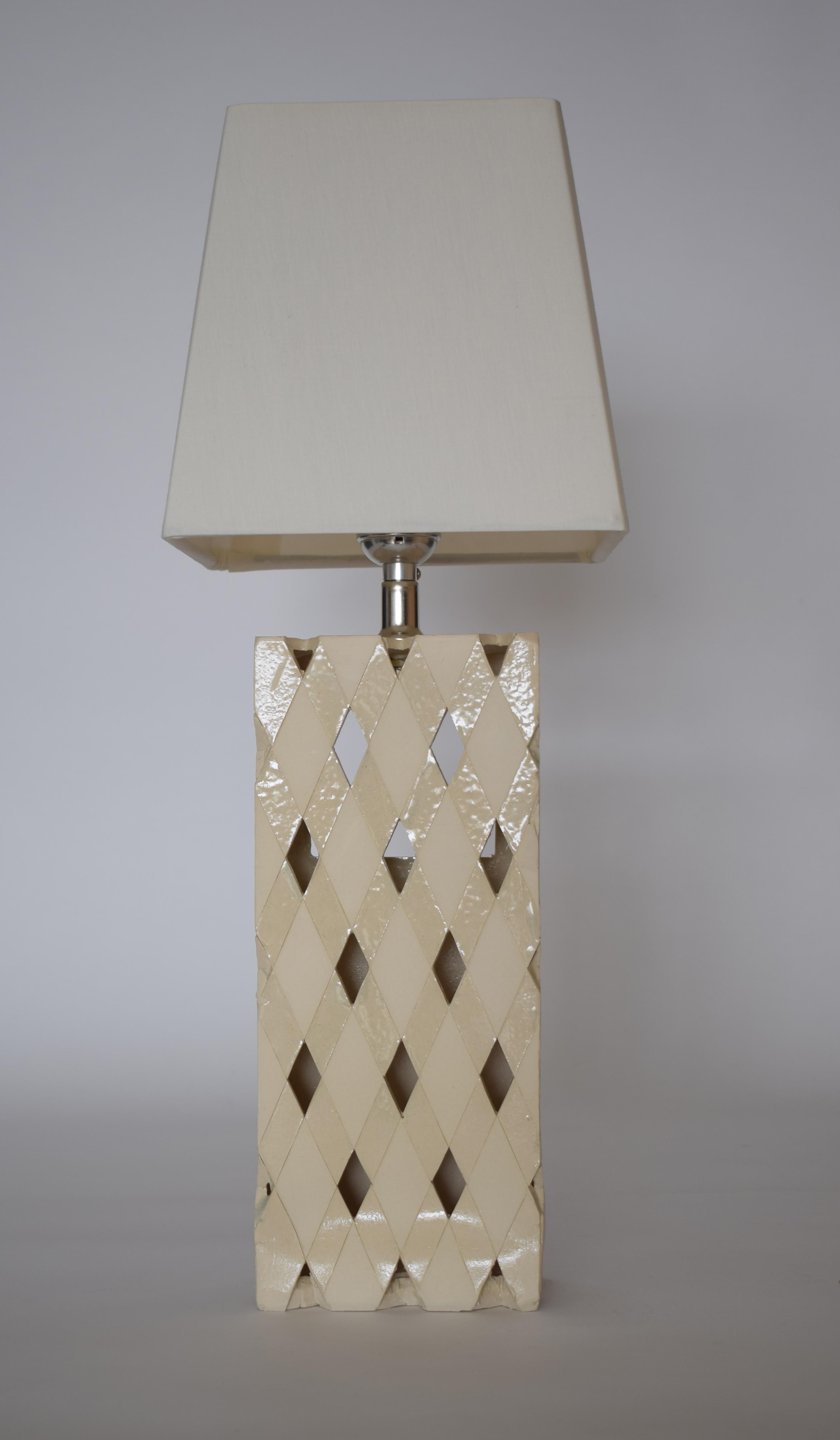 Introducing our stunning architectural lamp, inspired by the iconic Hearst building in NYC. Crafted with precision and sophistication, this one-of-a-kind piece features a rectangular clay prism adorned with an array of diamond openings. Drawing