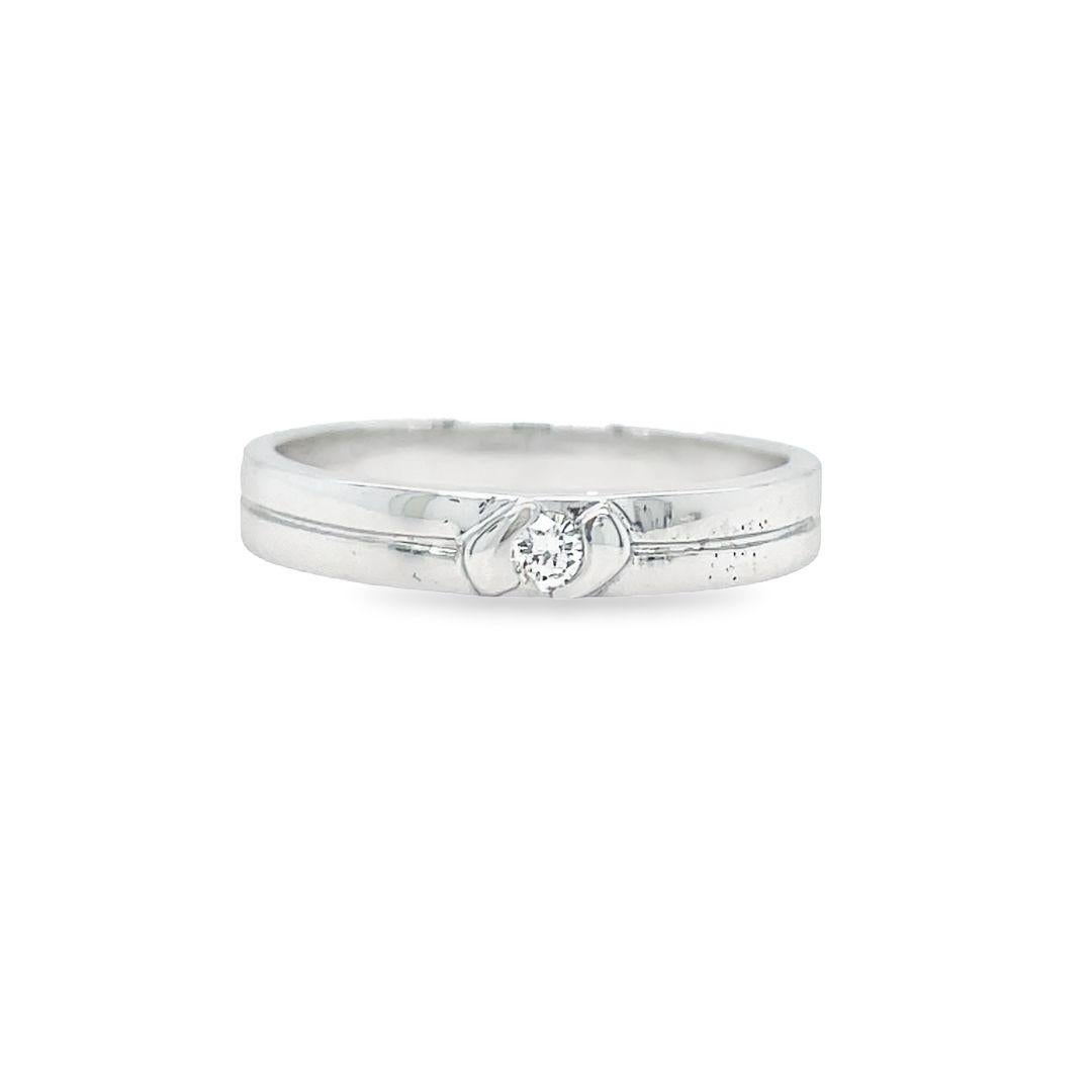 This band has a sleek profile and features one round brilliant cut diamond half-bezel set into the high polished band.  The diamond weighs 0.08 carat with G color and VS clarity. Crafted in 18K white gold, the metal beautifully reflects light,