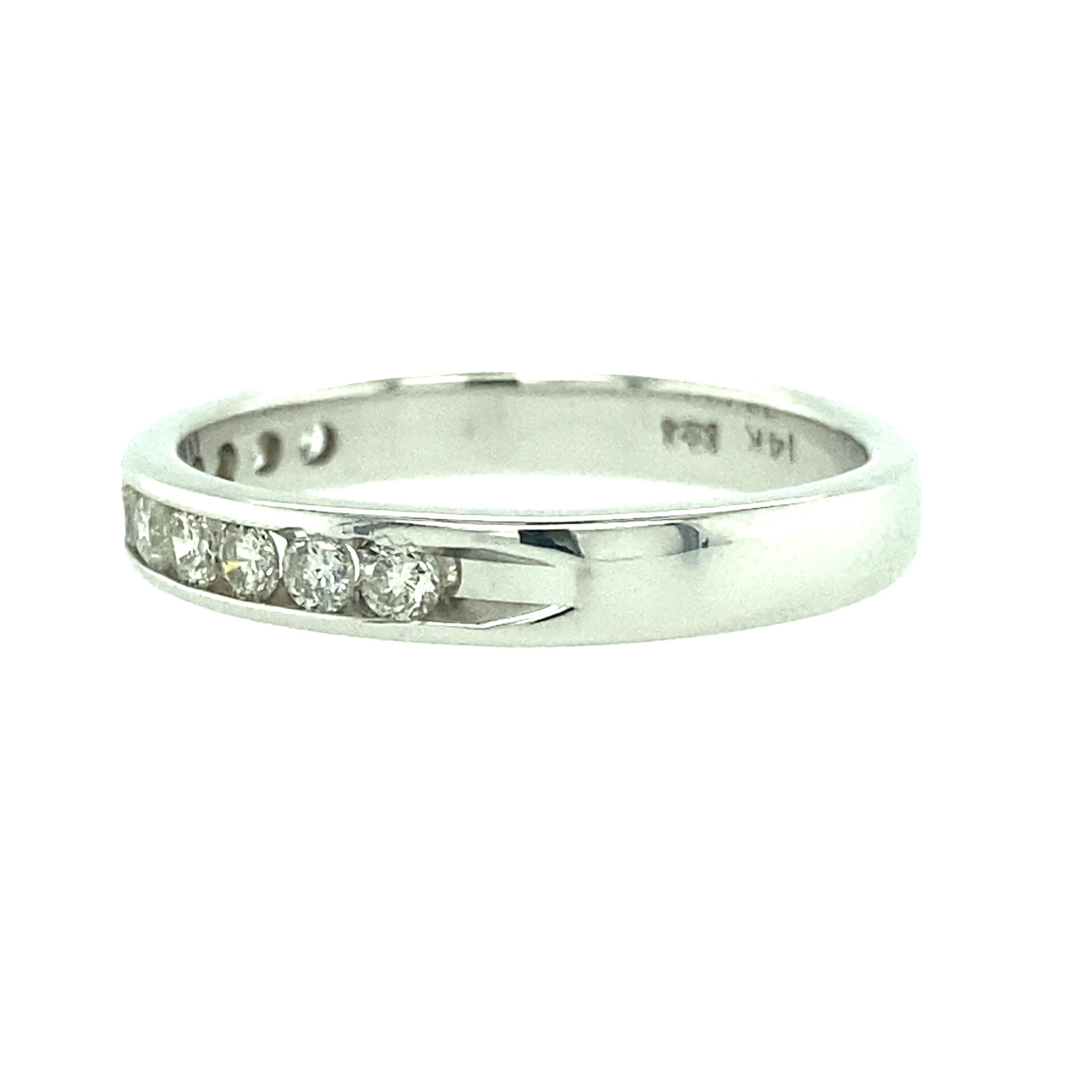 One 14 karat white gold (stamped 14K with hallmark) 3.30mm wide estate diamond wedding band set with eleven channel set diamonds, 0.33 carat total weight with matching 0.33 carat total weight with matching I/J color and SI clarity. Finger size 8.25