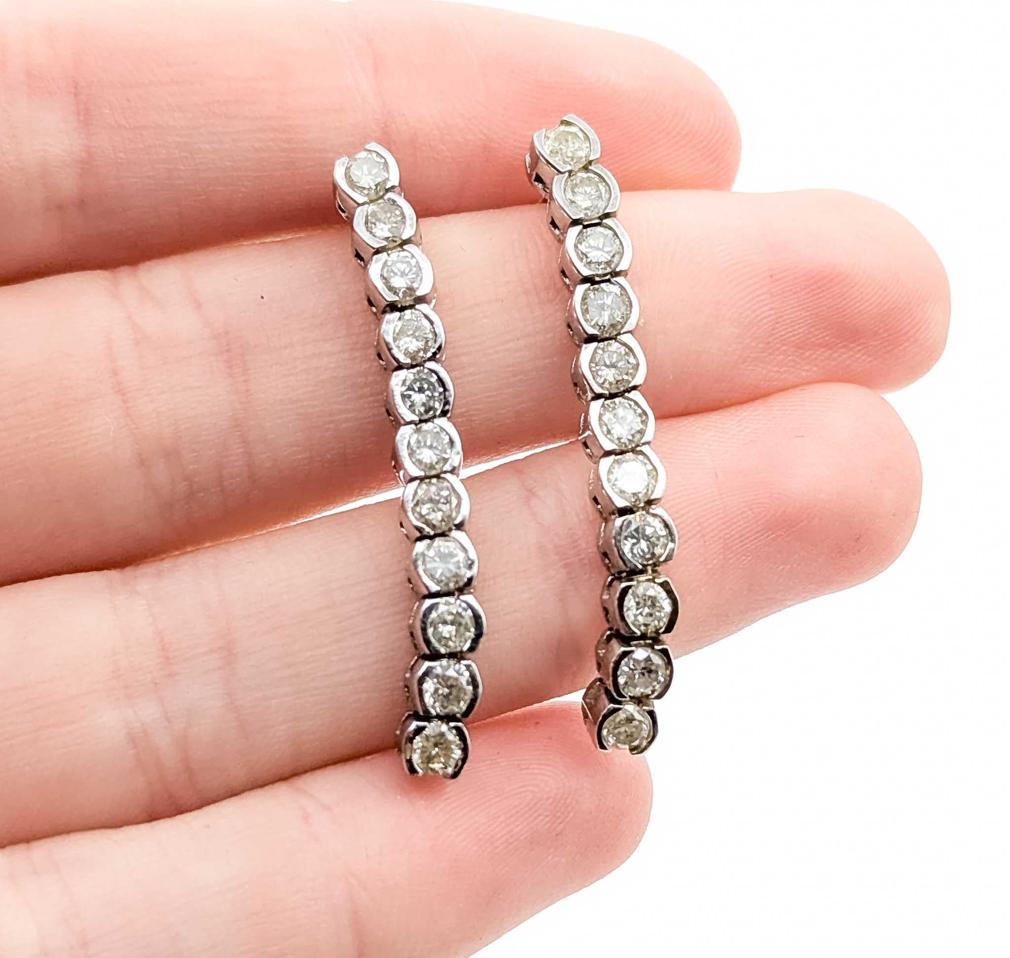 Diamond White Gold Earrings

Introducing these exquisite diamond earrings, masterfully crafted in 14k white gold with a bezel set dangle design. These elegant earrings feature a collection of sparkling diamonds totaling 2.20 carats, set in a