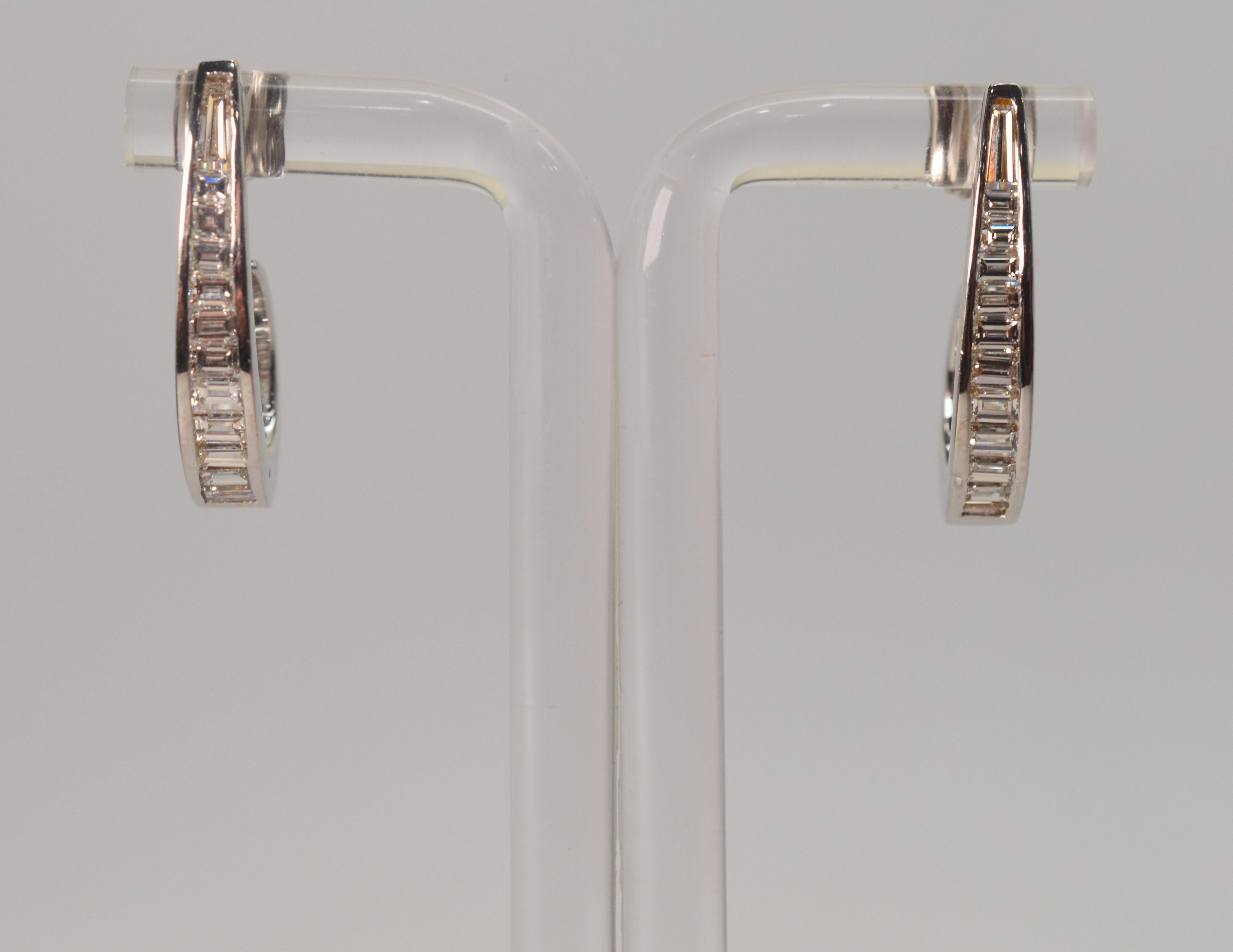Twenty four diamonds with a total weight of over a half carat are set in a channel on a J hoop of eighteen carat white gold. Outfitted with screw back posts for pieced ears, these earrings measure 3/4 inch from post to bottom.
