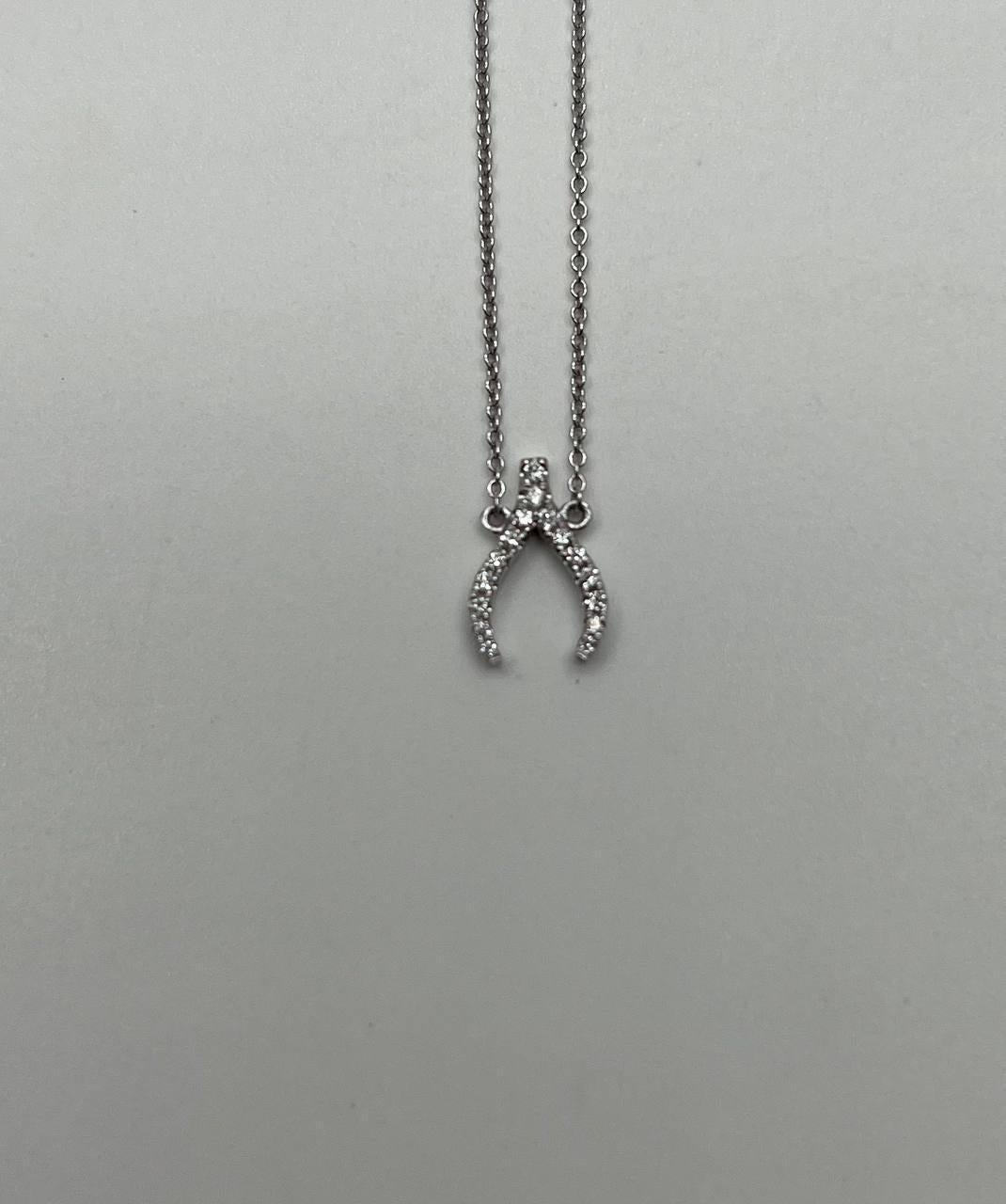 Ce collier pendentif est réalisé en or blanc 18 carats. Le pendentif présente un design en forme de bréchet orné de diamants blancs, totalisant environ 0,12 carats. La chaîne est délicate et complète la forme élégante du pendentif.