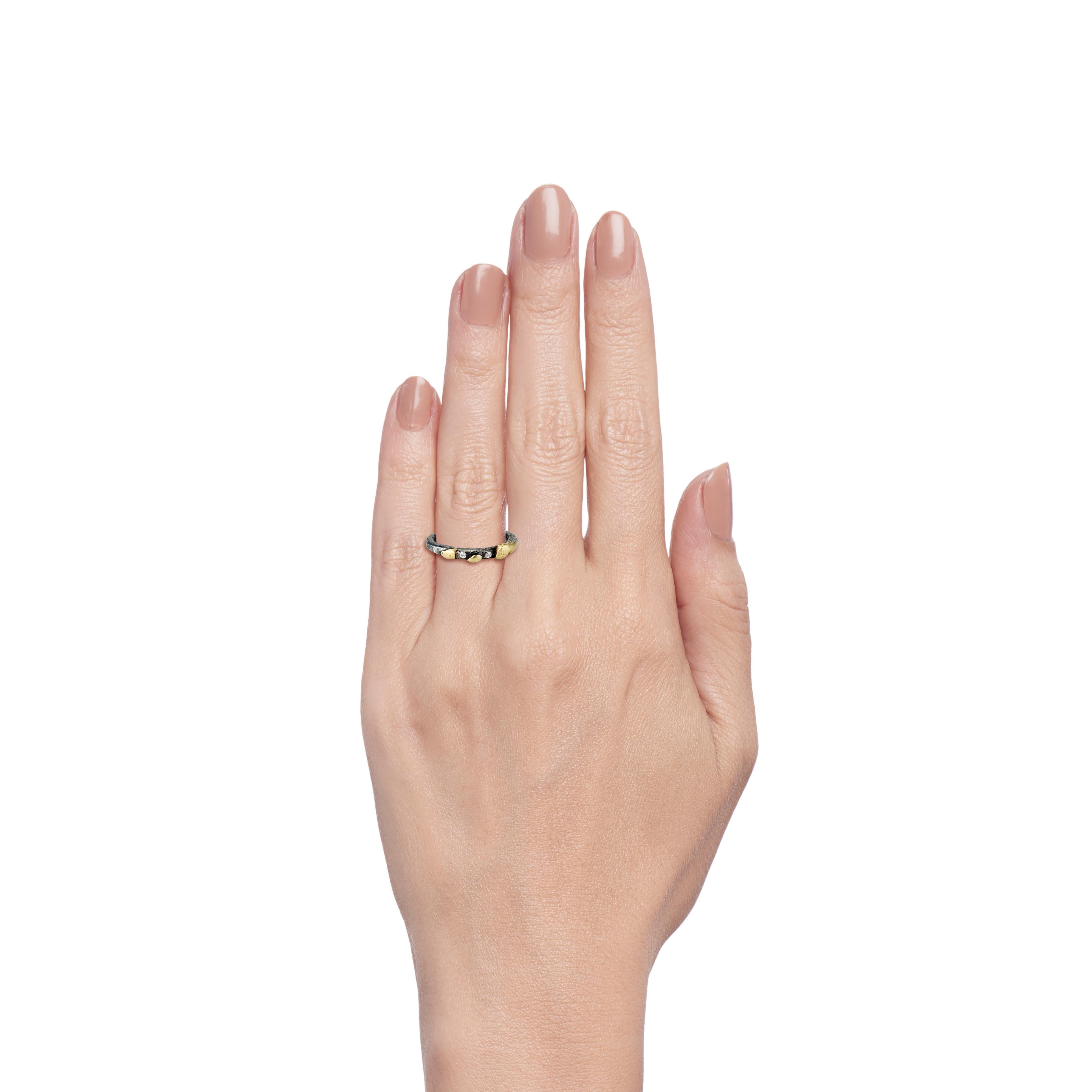 This charming skinny band ring starts with a 2mm band of Sterling Silver (size 5 1/2).  Next, shards of 22 karat yellow gold and three white round melee diamonds add texture, light and brightness.  The final part of the process is oxidizing the