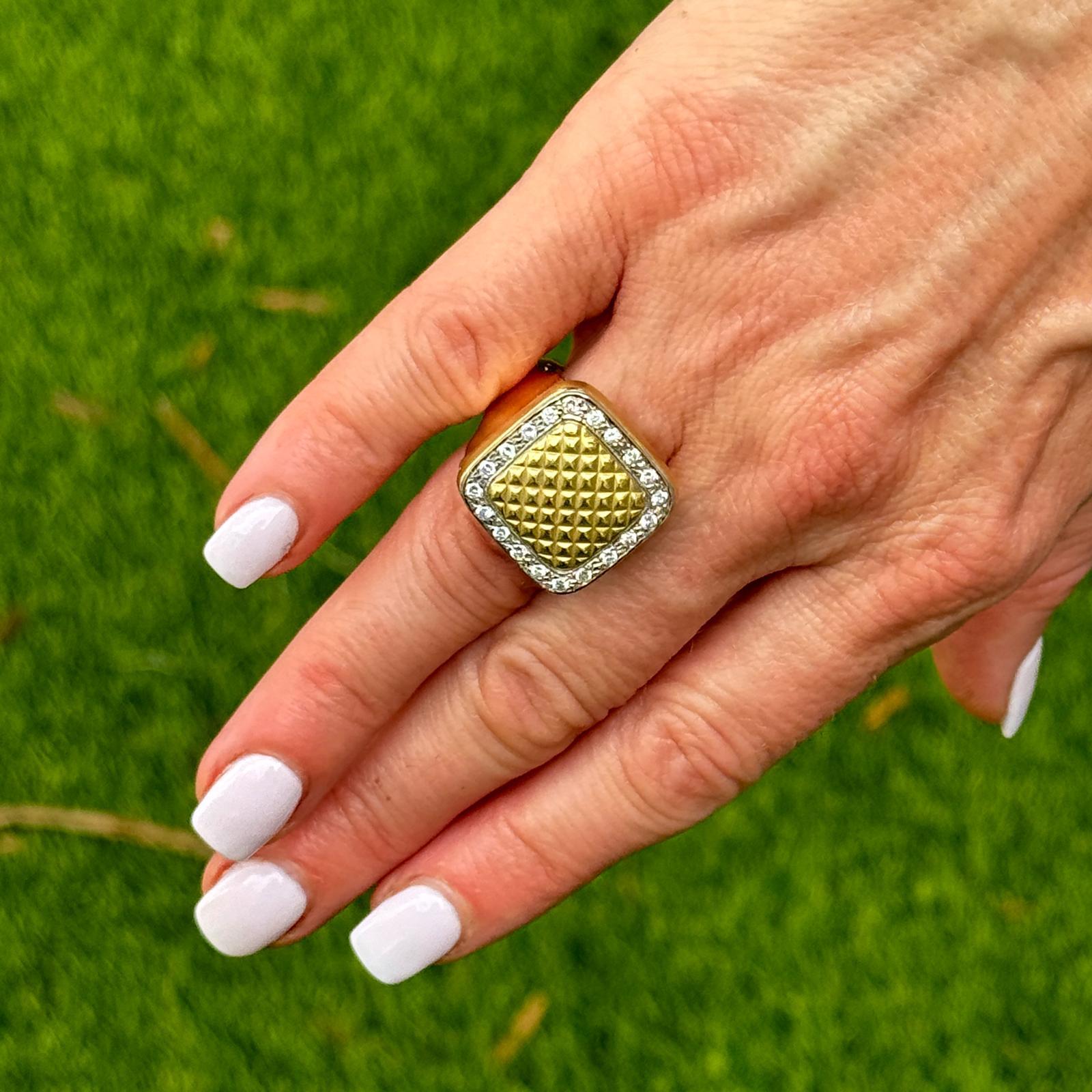 El punto focal de este anillo es una parte superior cuadrada perfilada por diamantes. El anillo, elaborado en oro amarillo de 18 quilates (espiga de oro amarillo de 14 quilates), está adornado con 20 diamantes redondos de talla brillante con un peso